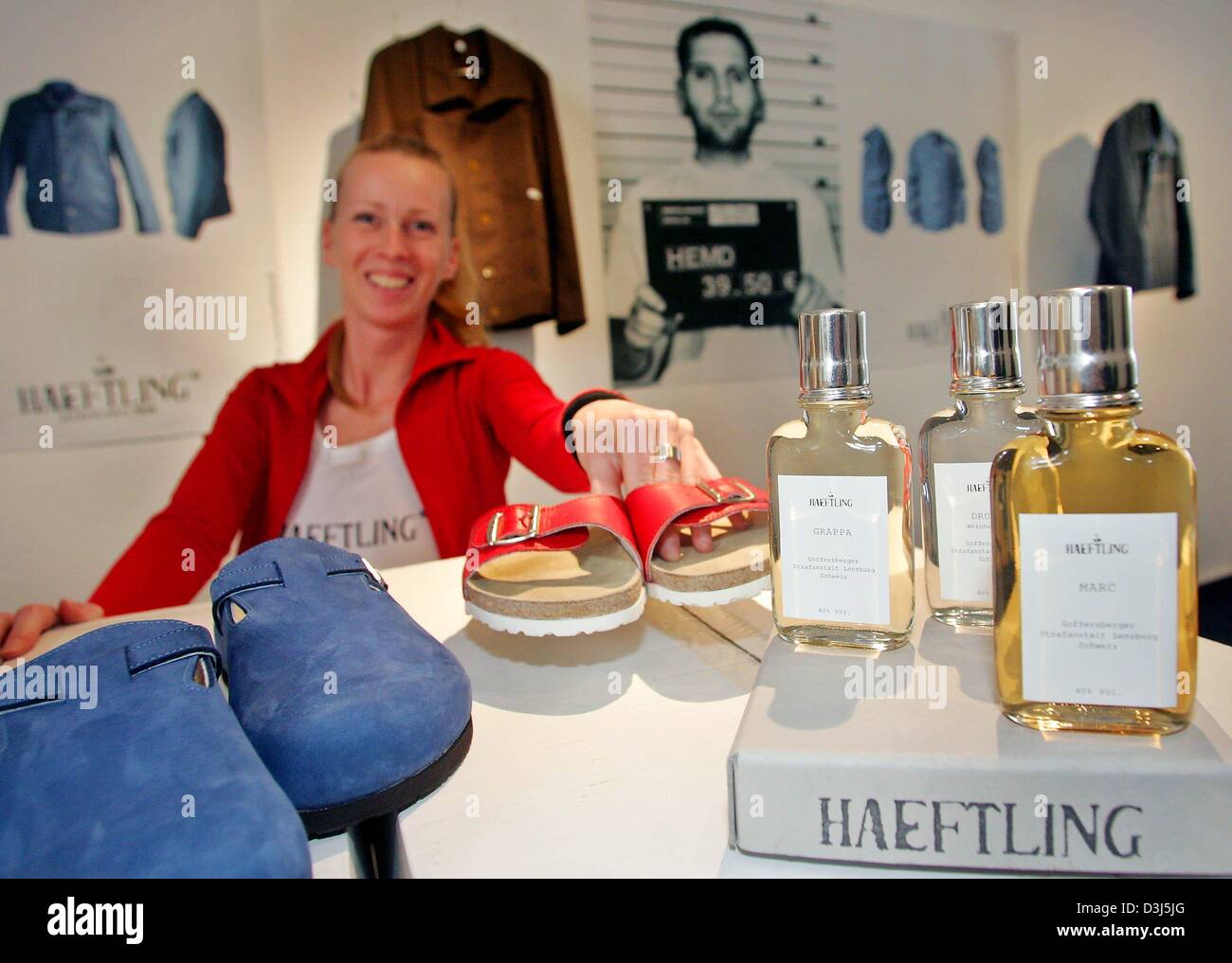 (dpa) - A sales assistant smiles as she presents slippers and parfumes on the occasion of the opening of a fashion and retail store which sells products and items manufactured by prison inmates in Berlin, 6 May 2004. The state penitentiary Tegel sells under the brand name 'Haeftling - Jailwear since 1898' shirts, jackets, shoes and bags via the internet. which is the first every Ha Stock Photo