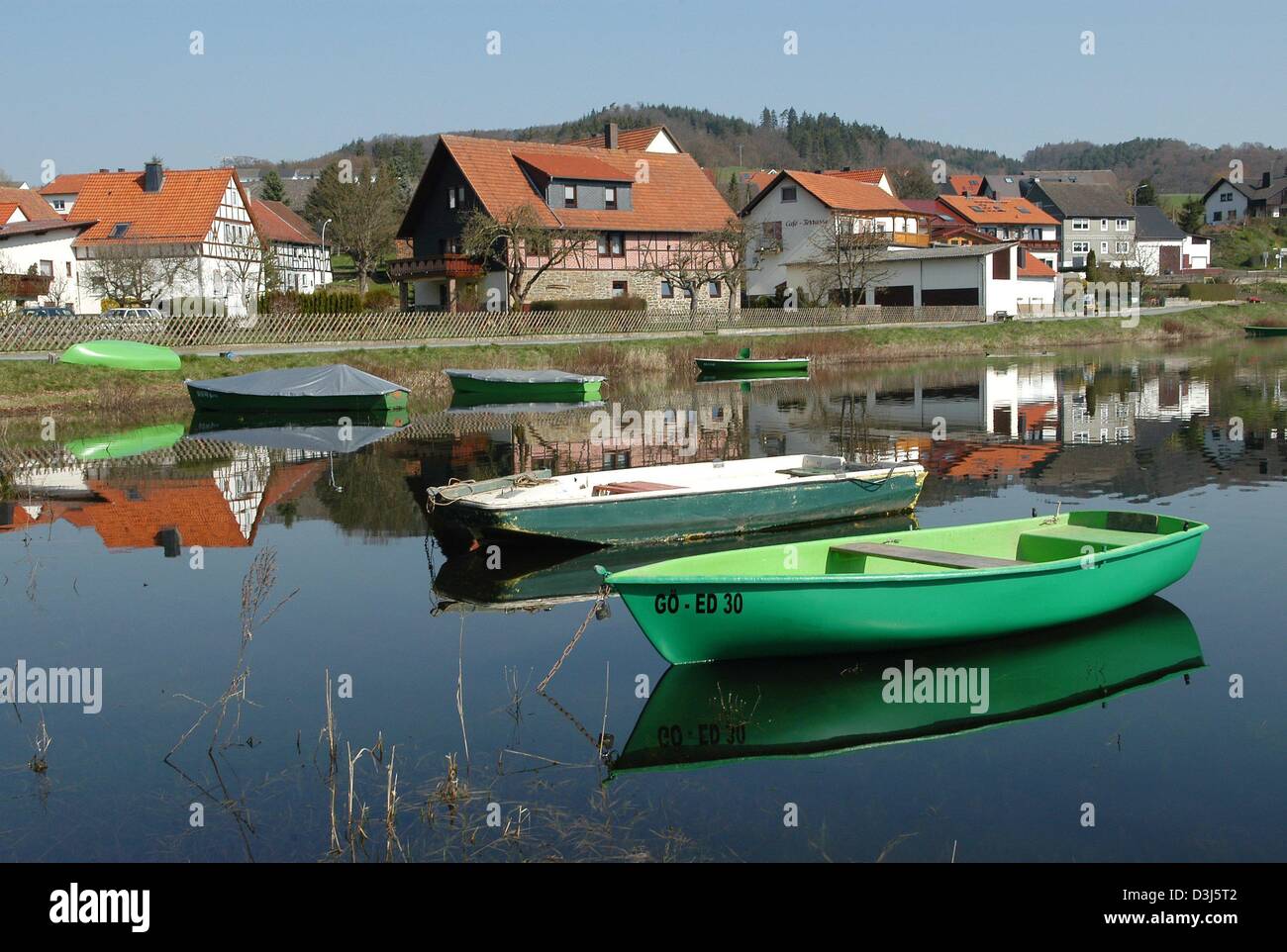 (dpa) - Small boats and the village of Herzhausen are reflected on the water surface of Lake Eder, western Germany, 15 April 2004. This area of the reservoir lake dries out every year in summer when the water level is sinking. Stock Photo