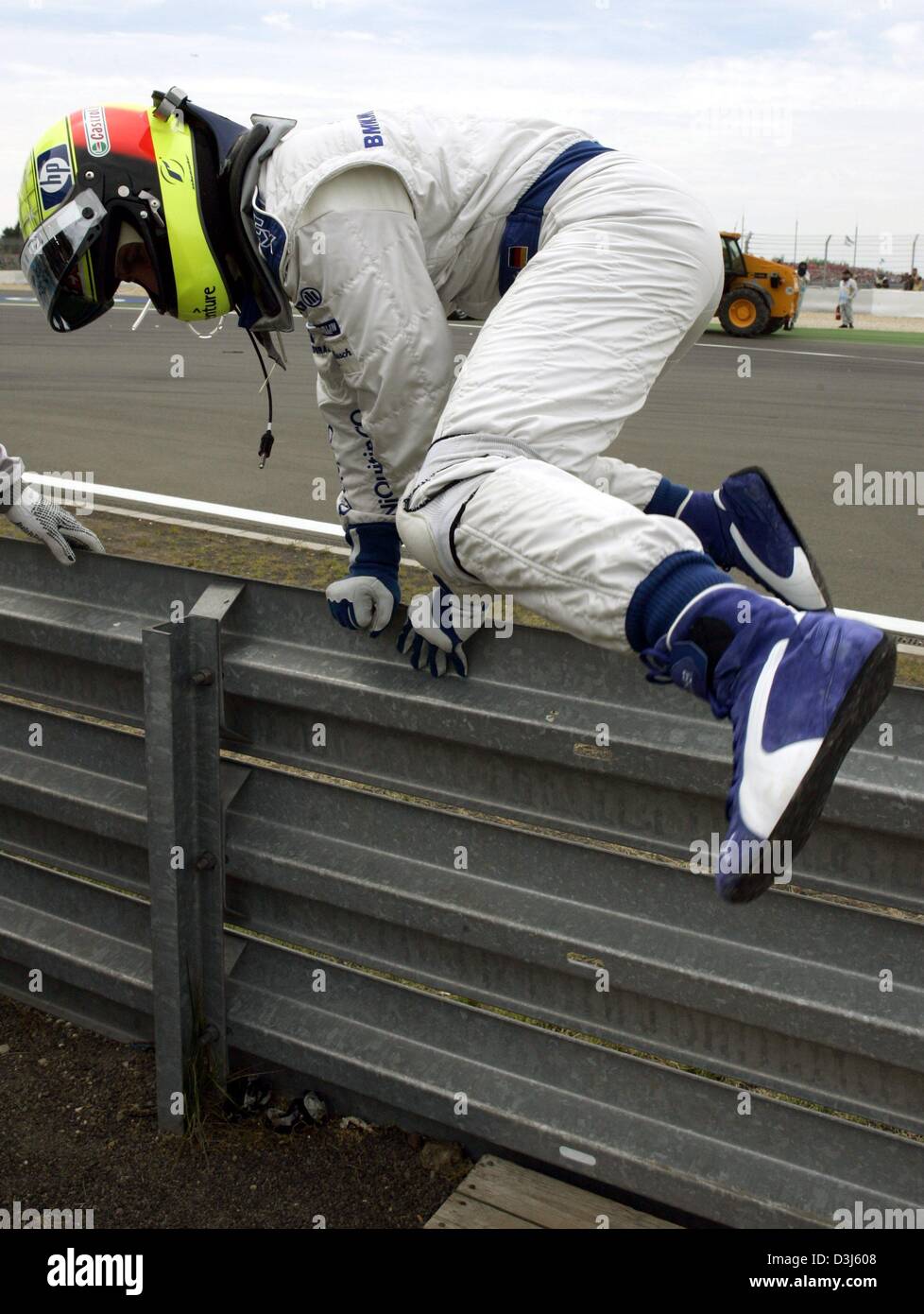 (dpa) - German formula one pilot Ralf Schumacher (BMW-Williams) climbs over the crash barrier after his accident during the European Grand Prix at the Nuerburgring race track in Germany, 30 May 2004. Stock Photo