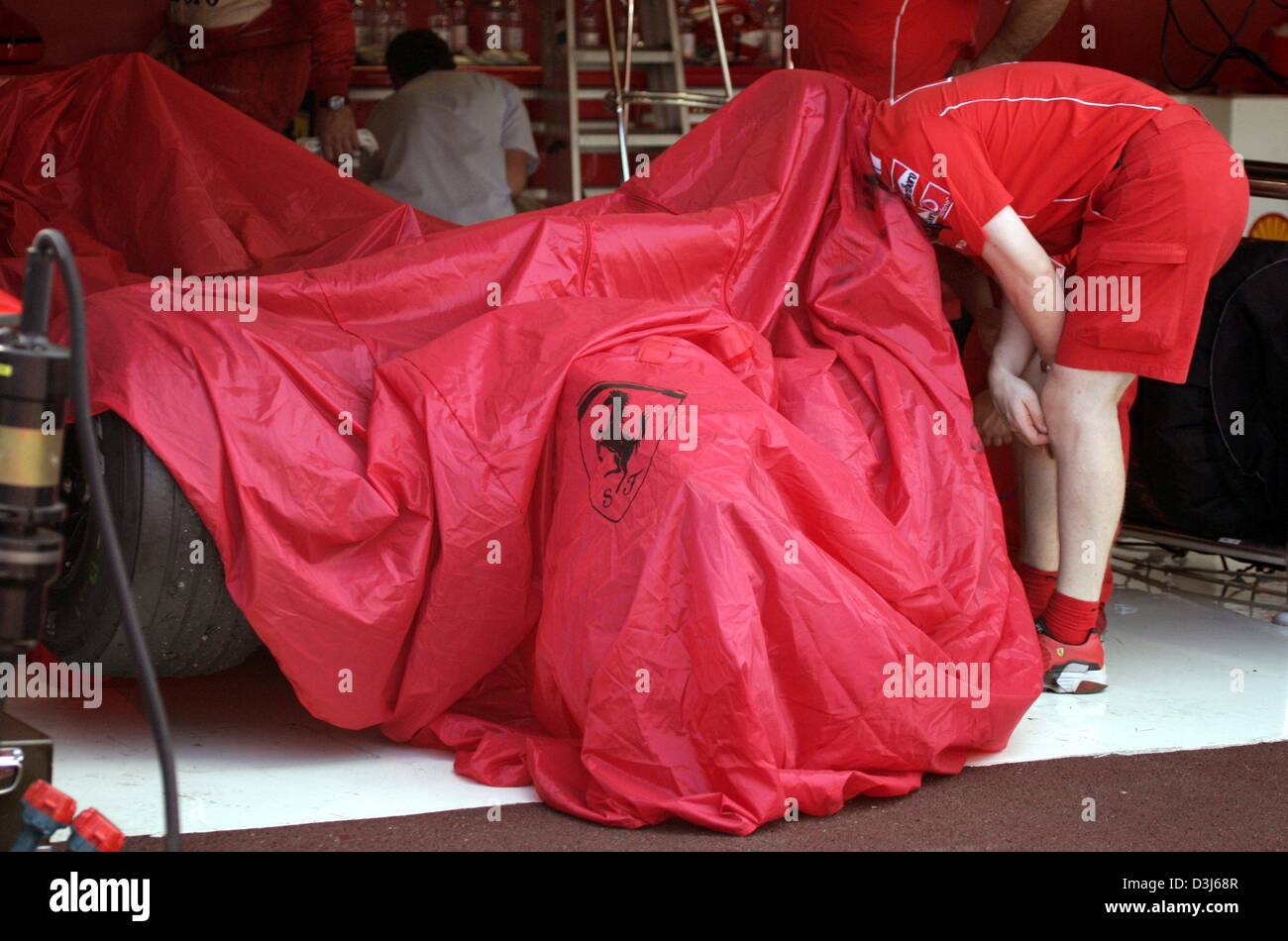 (dpa) - A Ferrari mechanic examines the formula one racing car of German formula one champion Michael Schumacher in the pit after the Formula 1 Grand Prix of Monaco, 23 May 2004. Schumach's was damaged after a crashed  with Colombian formula one pilot  Juan Pablo Montoya during the race. Stock Photo