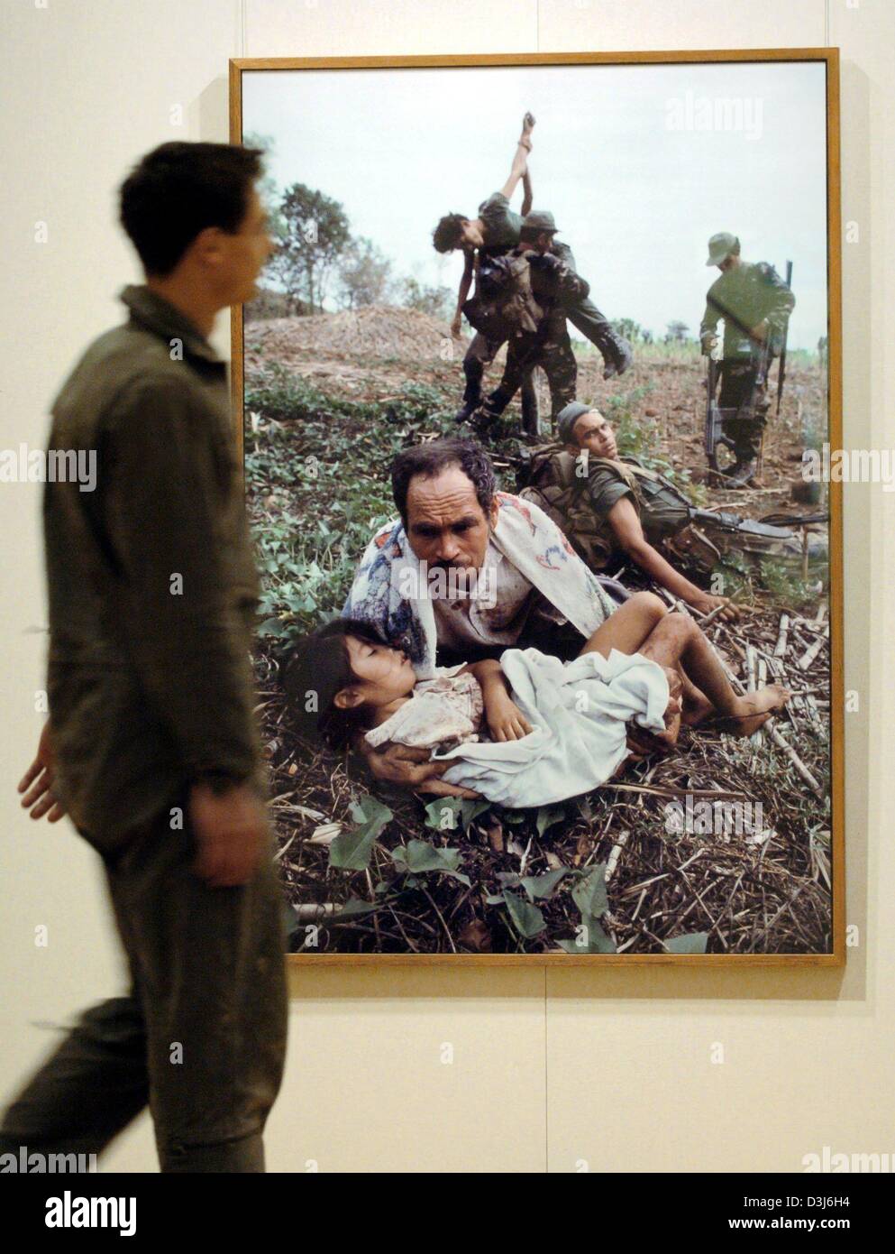 (dpa) - A visitor walks past a photograph by US photographer James Nachtwey at the art gallery of the Sparkasse in Leipzig, Germany, 6 May 2004. The exhibition features 132 photographs of this year's winner of the media prize and runs from 7 May to 30 May 2004. Nachtwey has been working as a photographer for the past 20 years covering war and misery throughout the world. Stock Photo