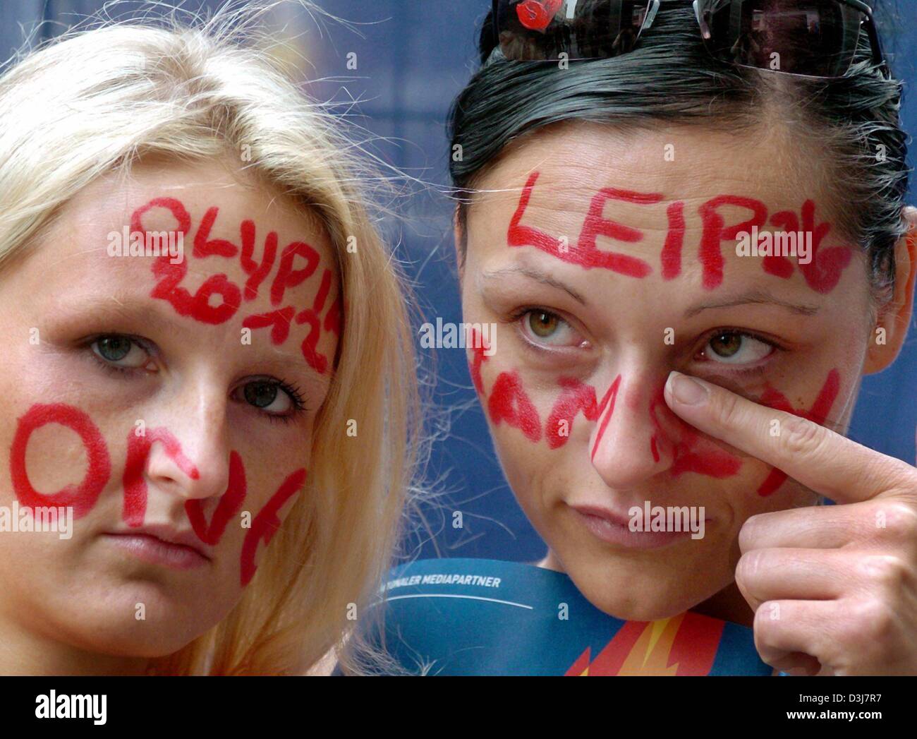 (dpa) - Two young women watch in disappointment the IOC's decision not to award the German city of Leipzig the official status as a candidate city to host the 2012 Olympic Games in downtown Leipzig, Germany, 18 May 2004. On huge screens in Leipzig thousands of people had watched a live feed from Lausanne, Switzerland, where the IOC (International Olympic Committee) decided to deny  Stock Photo