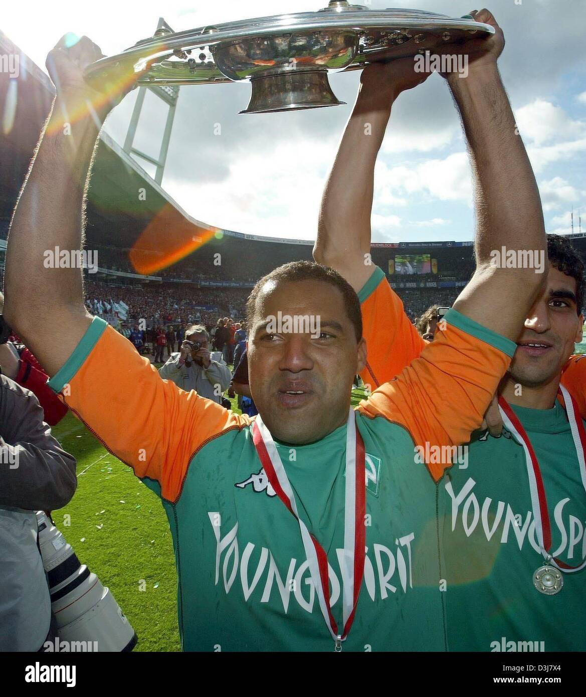 (dpa) - Bremen's Brazilian forward Ailton and Paul Stalteri (R) hold aloft the German Bundesliga champions trophy during celebrations in Bremen, 15 May 2004. after the Bundesliga soccer game opposing SV Werder Bremen and Bayer 04 Leverkusen in Bremen, Germany, 15 May 2004. Bremen lost the game 2-6. However, Bremen had already secured the 2003/2004 Bundesliga champion's title in the Stock Photo