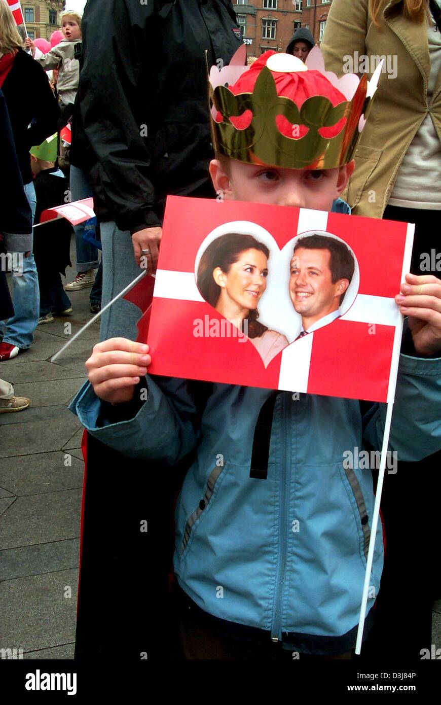 (dpa) - A little boy with a plastic crown holds up a Danish flag with a picture of Crown Prince Frederik and his fiancee Mary Donaldson as the royal wedding couple poses on the balcony of the city hall in Copenhagen, Denmark, 12 May 2004. The Danish capital is getting ready for the royal wedding of Crown Prince Frederik which will take place in Copenhagen Cathedral on Friday 14 May Stock Photo