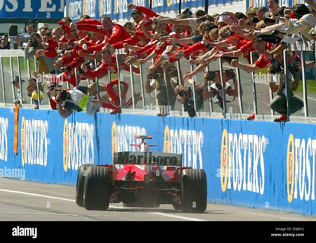 (dpa) - German formula one pilot and world champion Michael Schumacher (Ferrari) drives past his cheering mechanicsa aftere the Grand Prix of San Marino in Imola, Italy, 25 April 2004. Schumacher won the race ahead of British formula one pilot Jenson Button of BAR Honda and Colombian pilot Juan Pablo Montoya of BMW Williams. Located in the Apennine mountains of Italy, Imola has bee Stock Photo