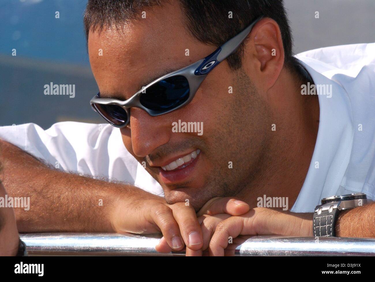 (dpa) - Colombian formula one pilot Juan Pablo Montoya (BMW-Williams) smiles as he leans on a metal bar at the driver's camp on the 'Enzo et Dino Ferrari' formula one circuit in Imola, Italy, 22 April 2004. The San Marino grand prix, which is the fourth race leading up to the 2004 formula one world championship, is going to start on Sunday, 25 April 2004. Stock Photo