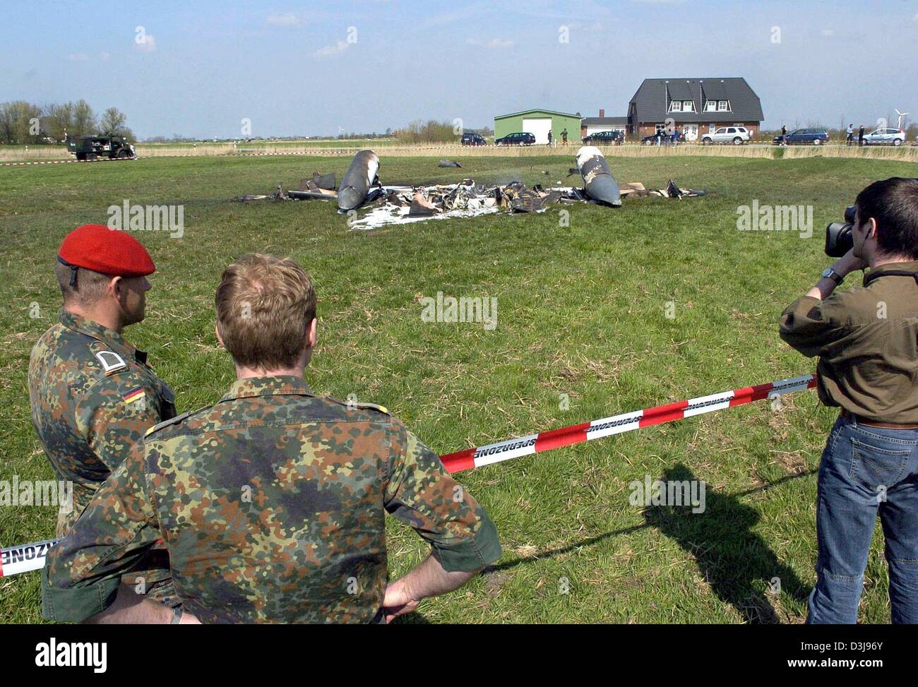 (dpa) - Soldiers and a cameraman stand next to the sealed-off wreckage of two German Tornado fighter jets which collided in mid-air near the town of Garding, northern Germany, on Wednesday, 21 April 2004. Two crew members were killed in the crash but two others were able to parachute to safety, police said. Stock Photo