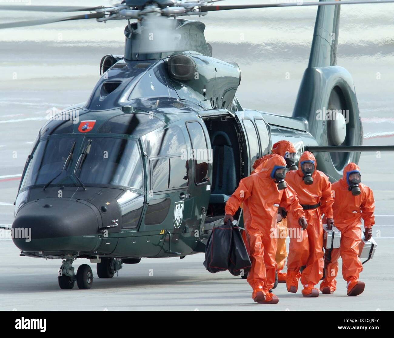 (dpa) - Experts of the Federal Border Guards (BGS), dressed in protective orange clothing walk away from a chopper after arriving at the airport during a safety and security exercise in Frankfurt Main, Germany, 31 March 2004. The joined exercise of the Federal Border Guard, customs, the fire brigade and the government agency for radiation protection took place under the name 'Hawke Stock Photo