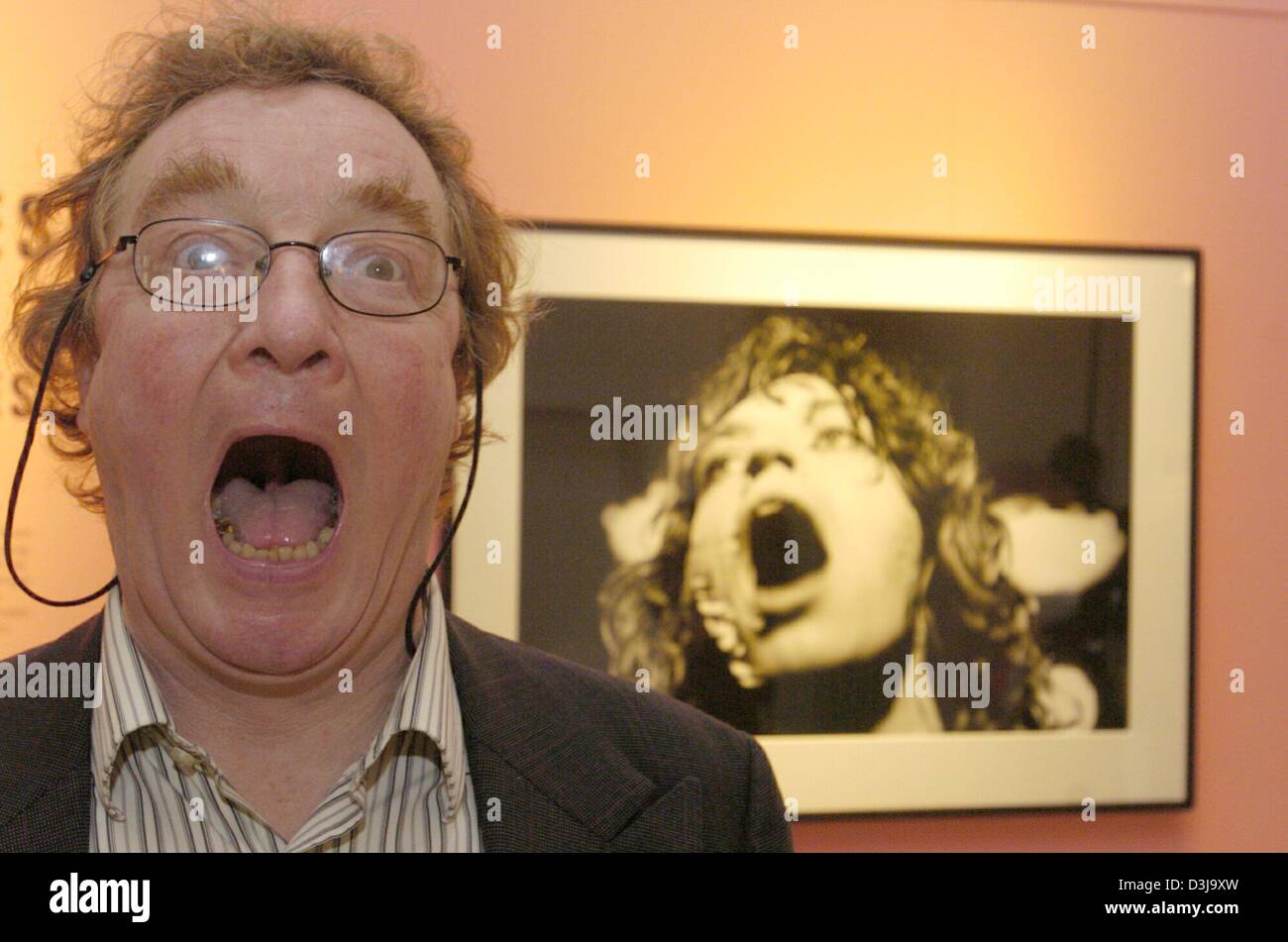 (dpa) - British photographer Christopher Simon Sykes stands next to a picture of Mick Jagger imitating the same facial expression at the Rolling Stones picture exhibition in Duesseldorf, Germany, 18 March 2004. The exhibition, which runs until 18 April, features around 60 photographs of a picture diary which Sykes compiled when he accompanied the Rolling Stones on their 'Tour of th Stock Photo