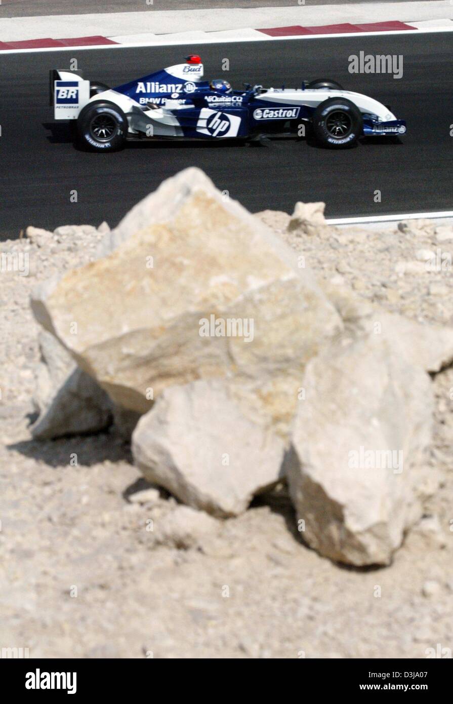 (dpa) - Colombian formula one pilot Juan Pablo Montoya steers his BMW-Williams around a curve passing a rock in the foreground on the new formula one race course in Manama, Bahrain, 2 April 2004. Montoya drove the second fastest time in the second free practise session in Bahrain. The Formula 1 Grand Prix of Bahrain will take place for the first time this Sunday, 4 April 2004. Stock Photo
