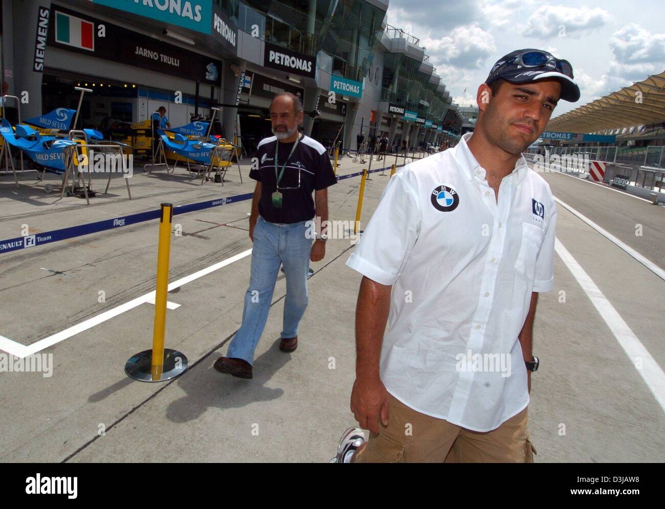 (dpa) The Colombian F1 pilot Juan Pablo Montoya (BMW-Williams) and his father (left-no first name given) stroll through the paddock area of the Sepang racetrack near Kuala Lumpur on Thursday, 18 March 2004. On Sunday, 21 March 2004, the Grand Prix of Malaysia will underway. Stock Photo