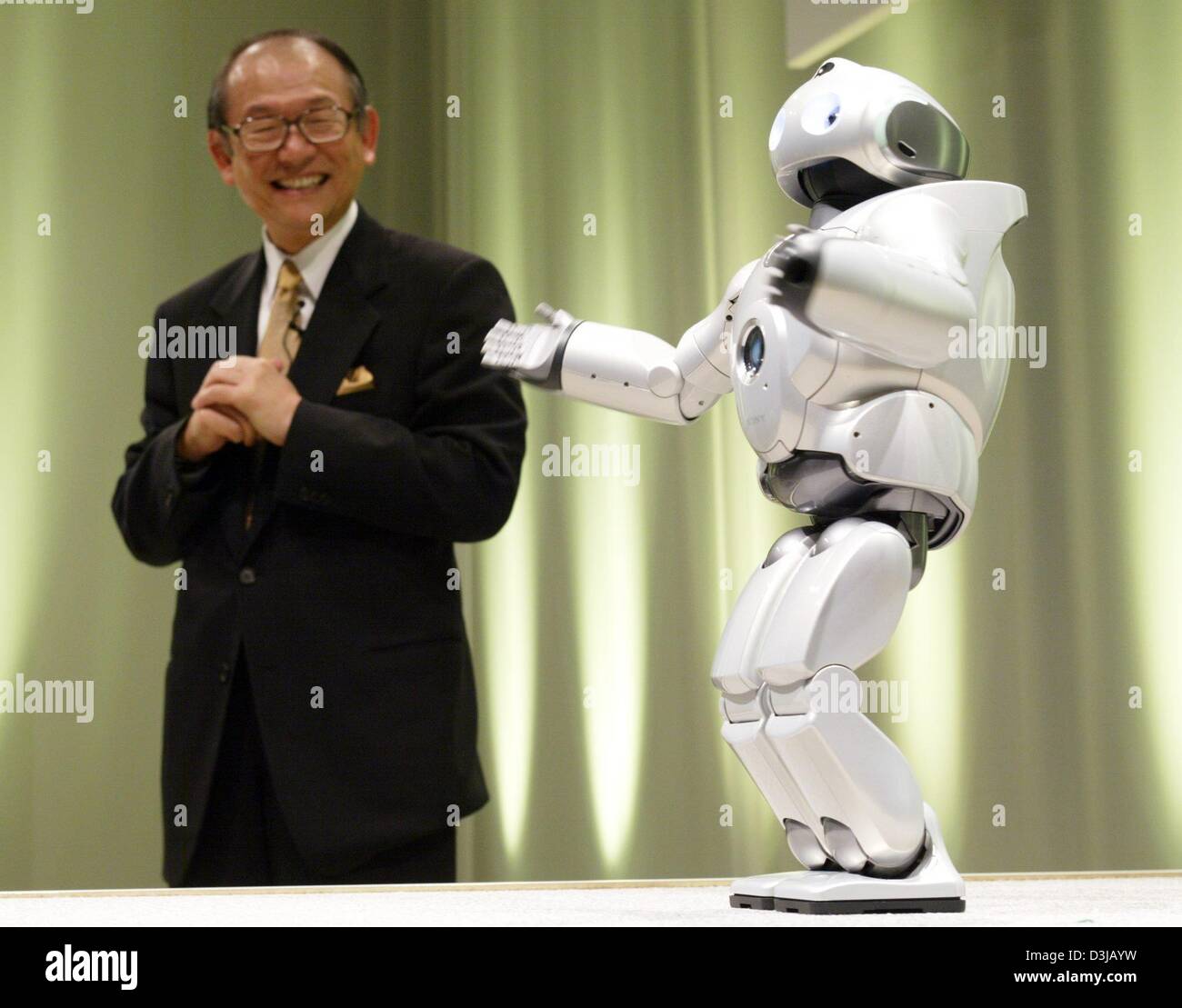 (dpa) - Kunitake Ando, President of Sony, stands next to the talking robot 'Qrio' during a press conference one day prior to the opening of the world's largest computer trade fair CeBit in Hanover, Germany, on Wednesday, 17 March 2004. 6,411 exhibitors and 500,000 visitors are expected to attend the fair which will run for seven days from 18 March. Stock Photo