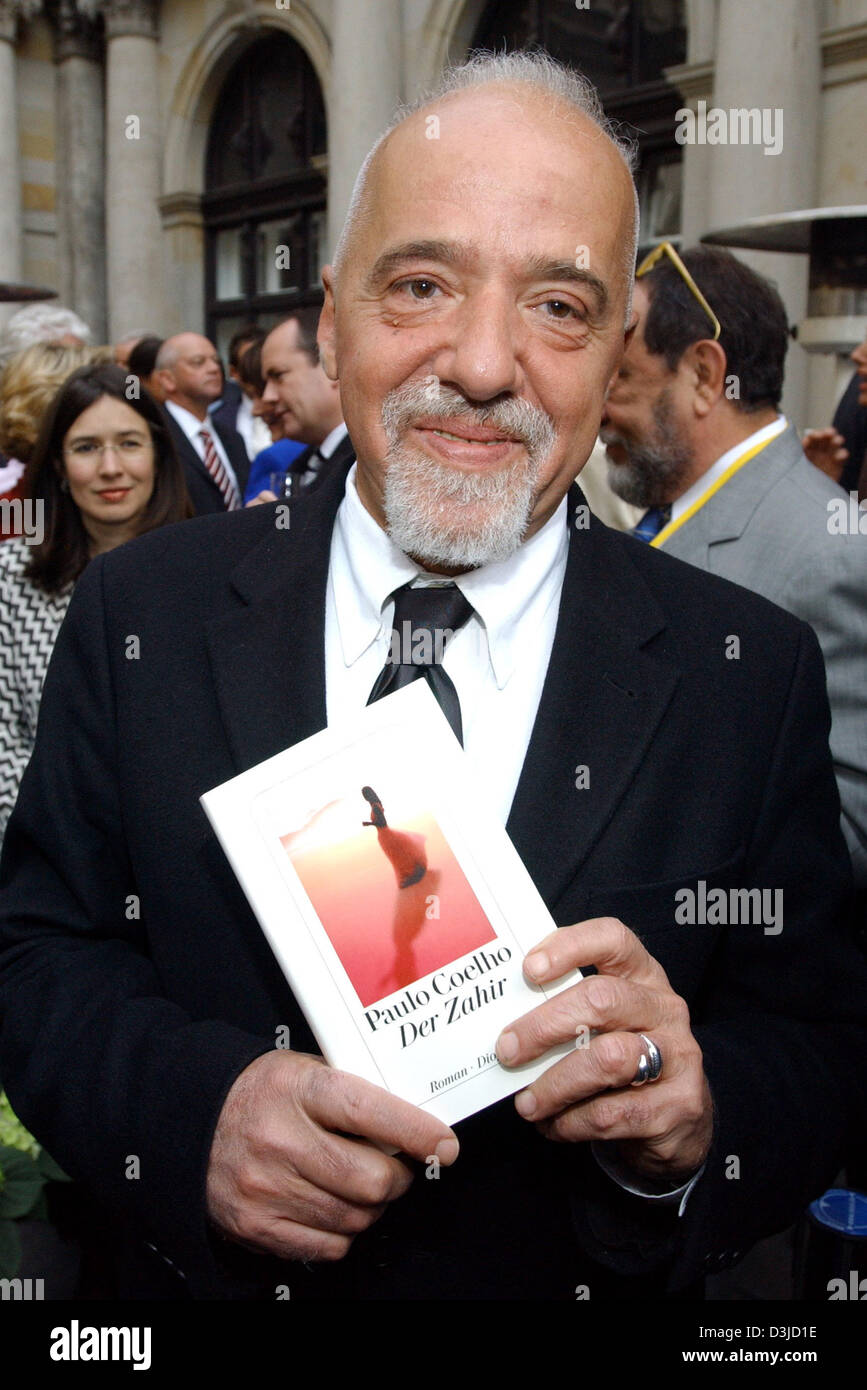 (dpa) - Brazilian author Paulo Coelho holds his latest novel 'The Zahir' in his hands and smiles as he arrives for the award ceremony at the chamber of commerce in Hamburg, Germany, 19 May 2005. Coelho received the 'Goldene Feder' (golden feather) media prize in the category 'honourary prize', which is being awarded by the Heinrich-Bauer publishing house. Stock Photo