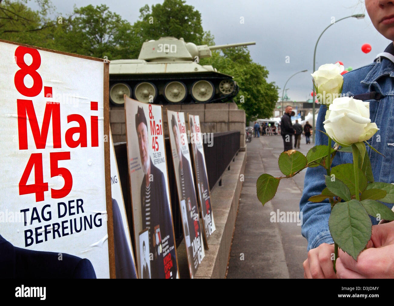 (dpa) - Two women hold white roses in their hands as they stand in front of a poster, which reads '8th May 45, Day of Liberation', at the Russian cenotaph during the 'Festival of Democracy' celebrations in Berlin, 07 May 2005. Several thousand people joined in the festivities at the Brandenburg Gate on the occasion of the 60th anniversary of the end of the Second World War. Stock Photo