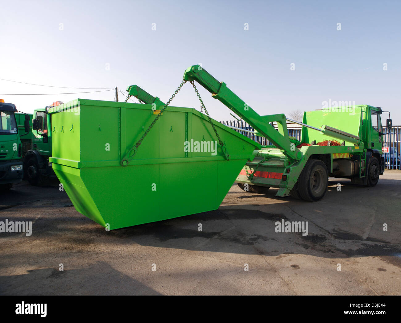 Green skip being hoisted onto a disposal truck Stock Photo