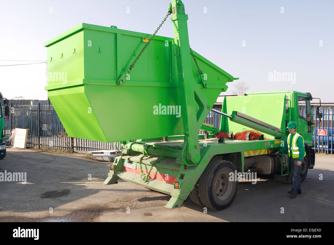Green skip being hoisted onto a disposal truck Stock Photo