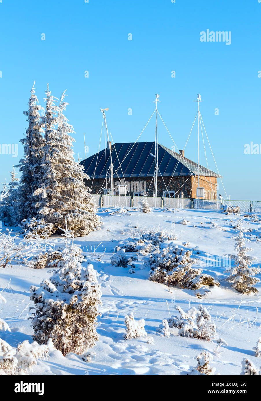 Winter fir and mountain weather station house in first morning sunbeams Stock Photo