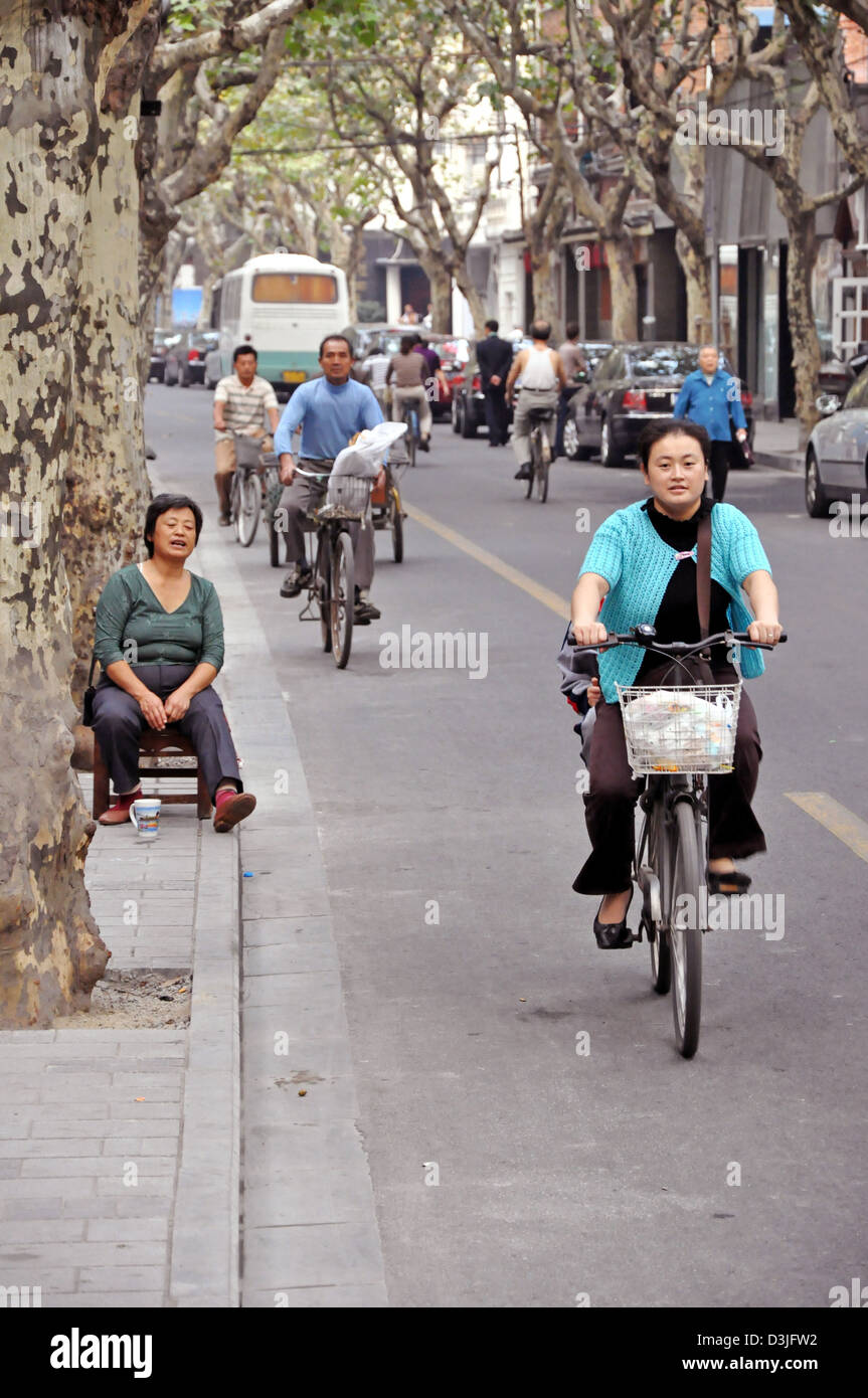 Chinese people riding bicycles in a street of the French Concession in Shanghai - China Stock Photo