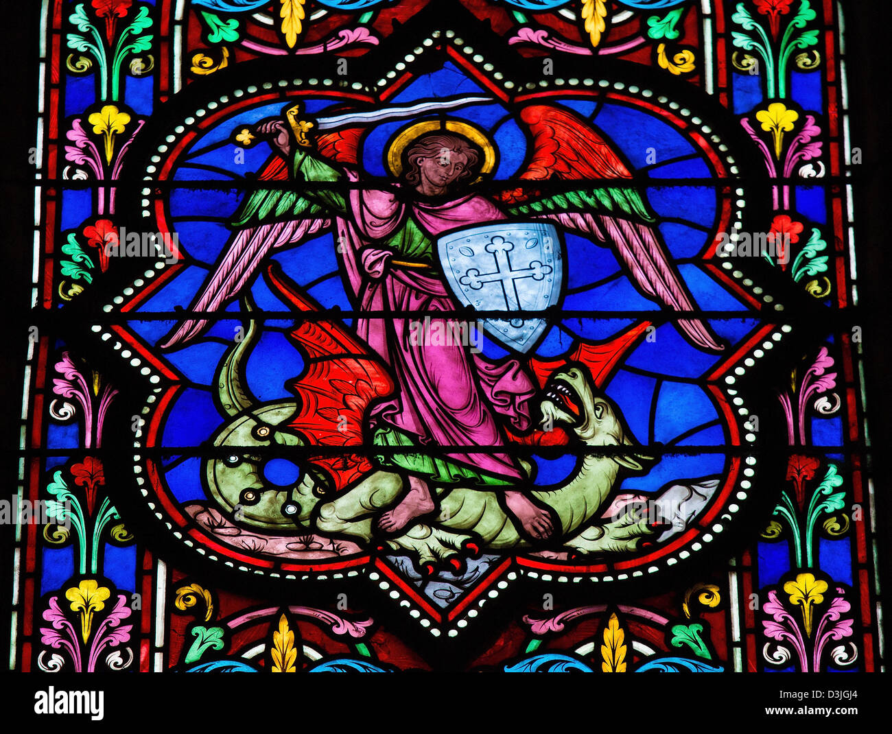 Stained glass window depicting Saint Michael the Archangel slaying Satan as a dragon Stock Photo