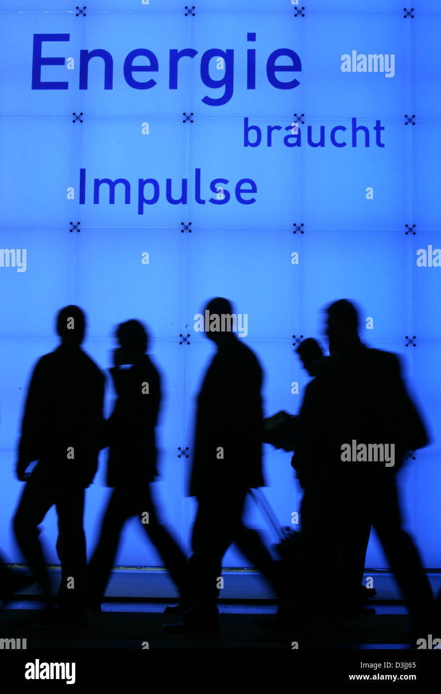 (dpa) - Visitors of the Hanover industry fair walk past a booth of an energy producer featuring the inscription 'Energie braucht Impulse' (energy needs impulses) in Hanover, Germany, 12 April 2005. About 6,100 exhibitors from 65 nations show their products in Hanover between 11 and 15 April 2005. Stock Photo