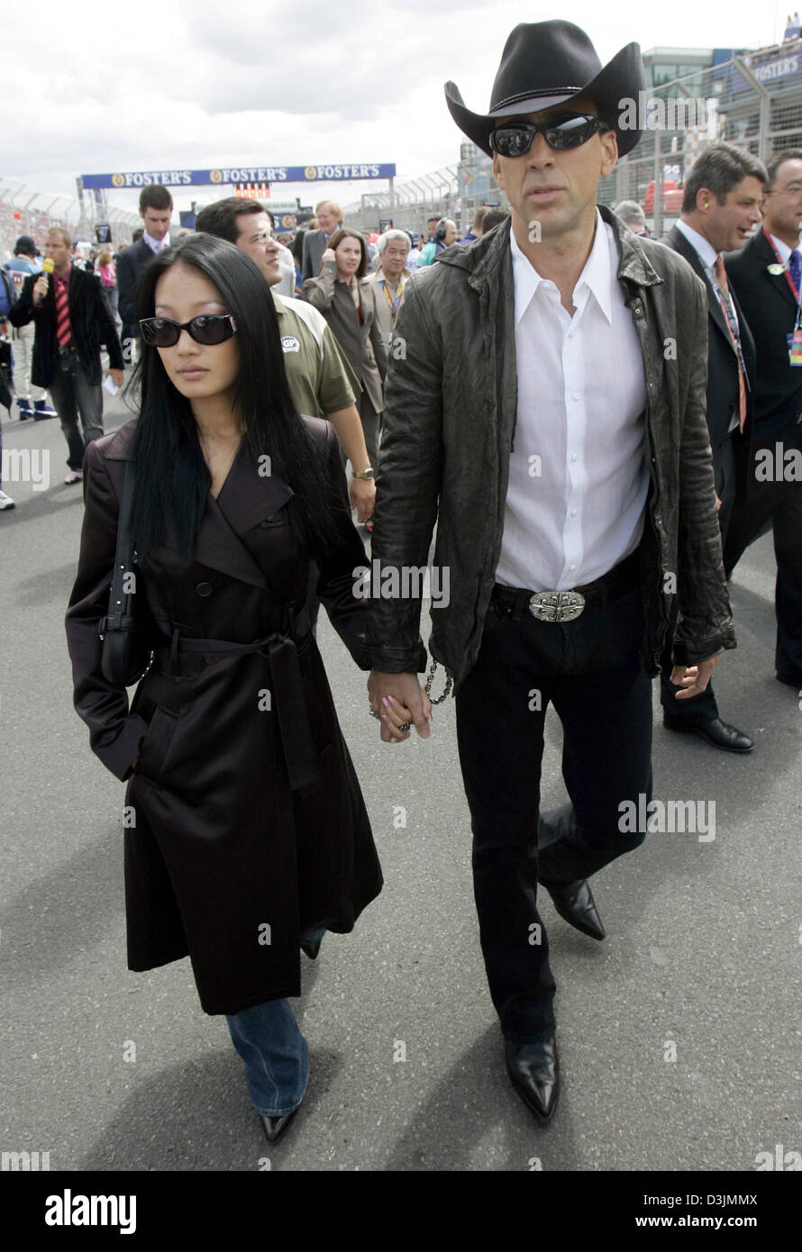 (dpa) - US actor Nicolas Cage and his third wife, former waitress Alice Kim, walk over the starting grid before the start of the Australian Grand Prix  in Melbourne, Australia, 06 March 2005. Italian formula one pilot Giancarlo Fisichella won ahead of Brazilian driver Rubens Barrichello and Fernando Alonso of Spain. Stock Photo