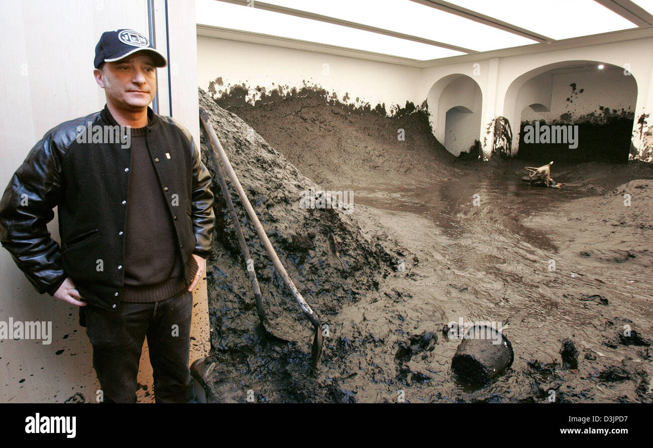 (dpa) - Spanish artist Santiago Sierra stands at the entrance to an  exhibition room which is filled with dirt and mud at an art gallery are filled with mud and dirt in Hanover, Germany on Thursday 10 February 2005.   Visitor can access the rooms but have to wear wellington boots. Sierra had 120 tons of dirt and mud delivered for his art project 'Haus im Schlamm' (house in the mud) Stock Photo