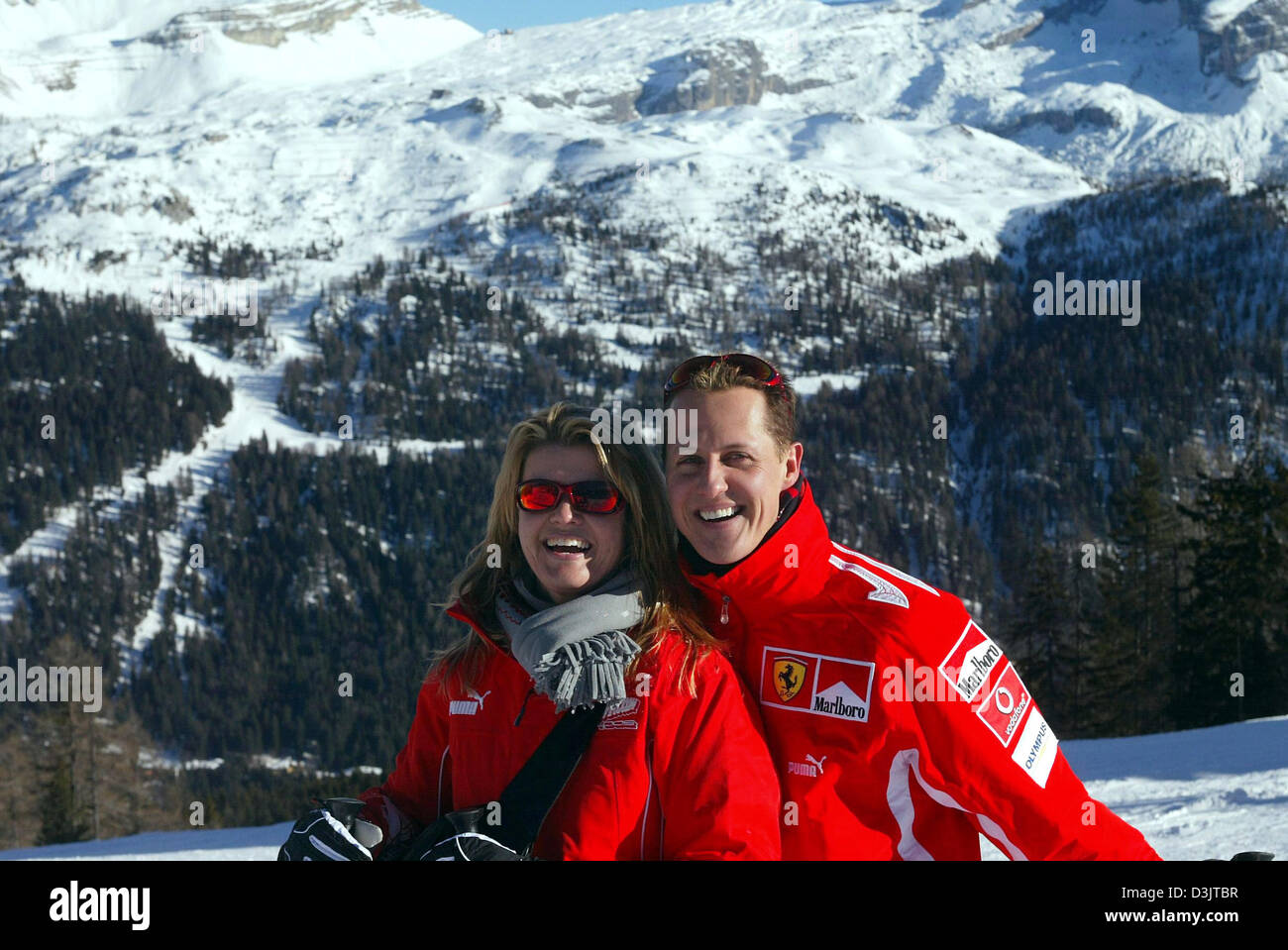 (dpa) - Seven time Formula 1 champion Michael Schumacher (R, team Ferrari) and his wife Corinna smile in front of a mountain panorama shortly after arriving in the ski resort of Madonna di Campiglio, Italy, 11 January 2005. The Ferrari team got together for its traditional ski vacation in the Italian Alps. (ITALY OUT) Stock Photo