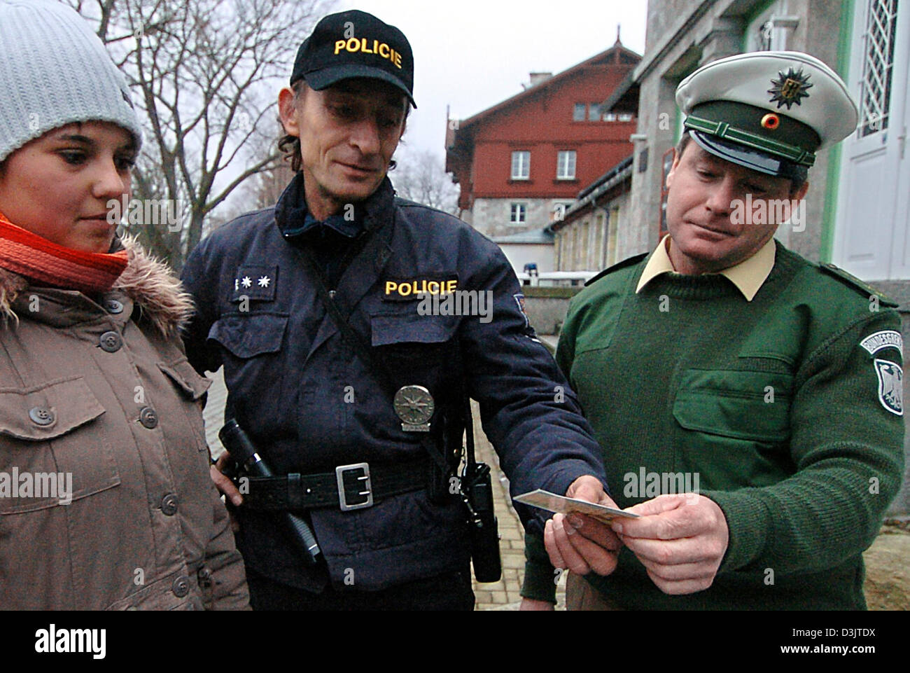 (dpa) - A Czech border guard (C) and his German colleague (R) inspect the identity card of a young woman at the Czech-German border corssing in Eisenstein, Germany, 6 December 2004. The trafficing of people currently proves to be profitable as ever. German Federal Border Guards (BGS) continue to track down refugees who attempt to cross the border into Germany illegally, despite the Stock Photo
