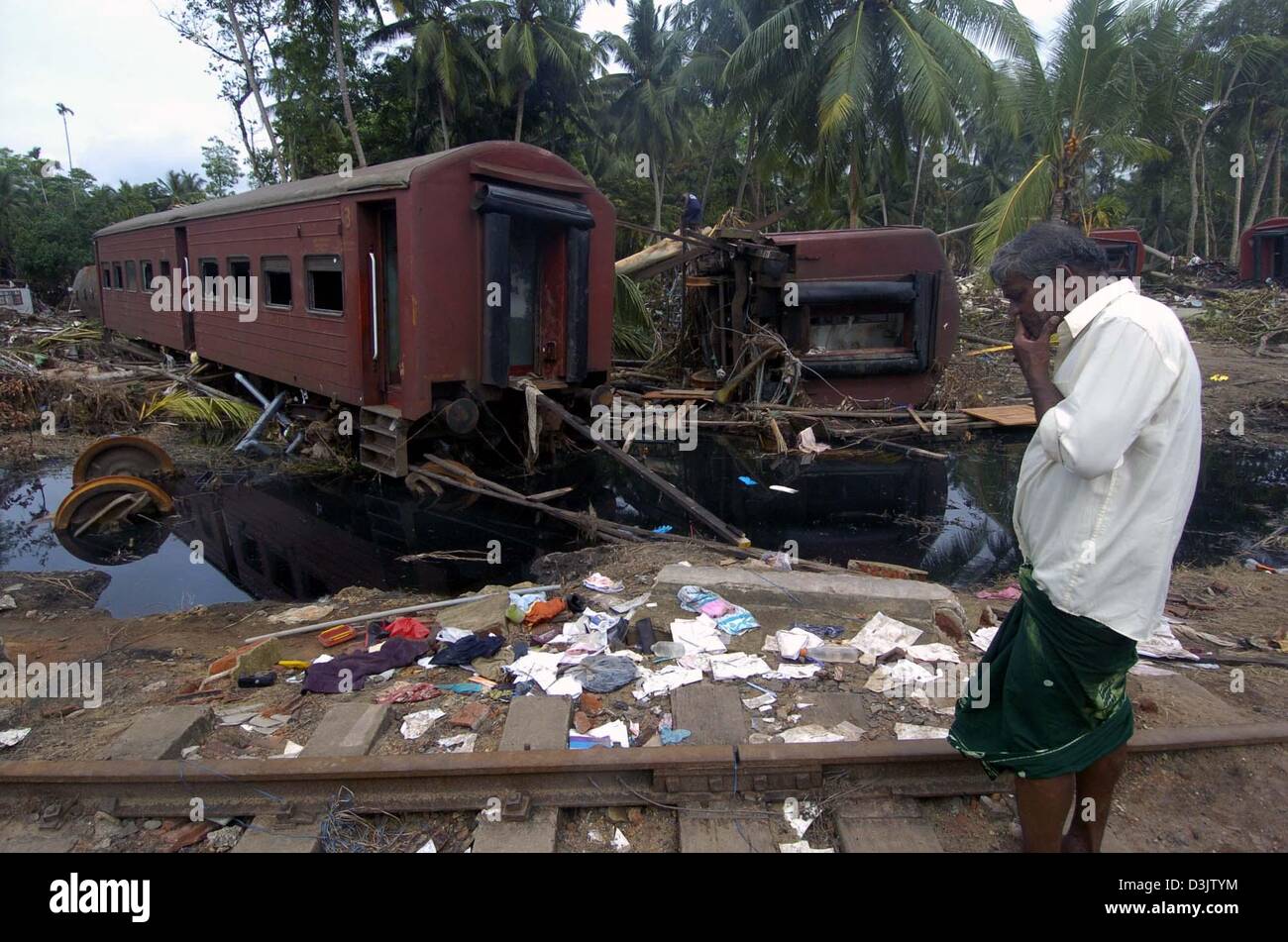 (dpa) - A man looks at a derailed train coach laying next to a destroyed house in the town of Dellewatha near the city of Galle, Sri Lanka, 2 January 2005. Hundreds of thousands of people living in the coastal areas of Sri Lanka lost their homes and around 30,000 people were killed by a devastating tsunami caused by a seaquake on 26 December 2004. Stock Photo