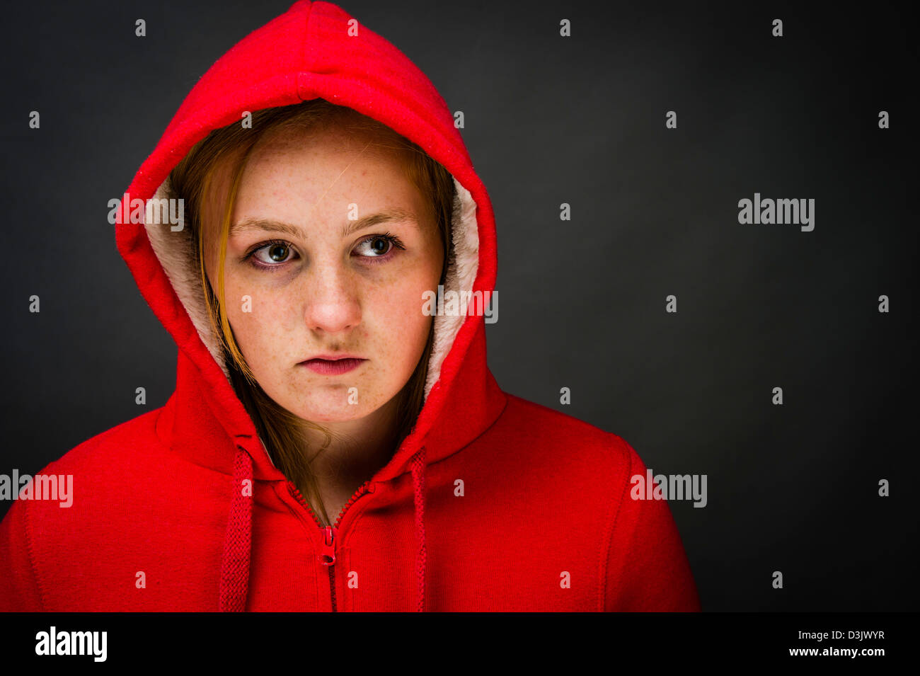 A moody sulky 16, 17 year old red haired freckle faced teenage girl, wearing a hoodie UK Stock Photo