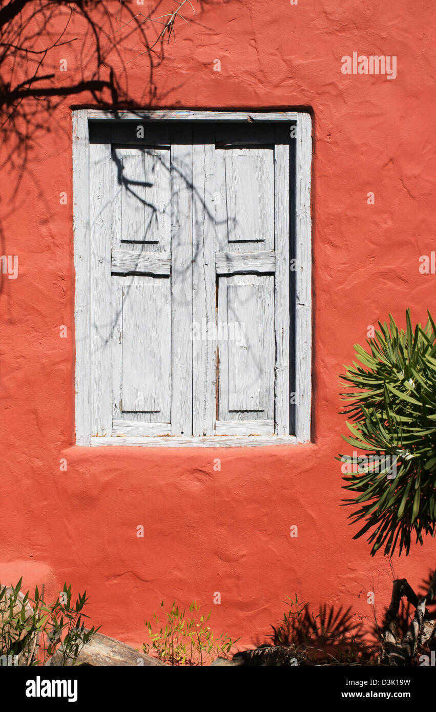 Faded blue grey wooden window shutters against an orange red wall Arteara, San Bartolomé de Tirajana Stock Photo