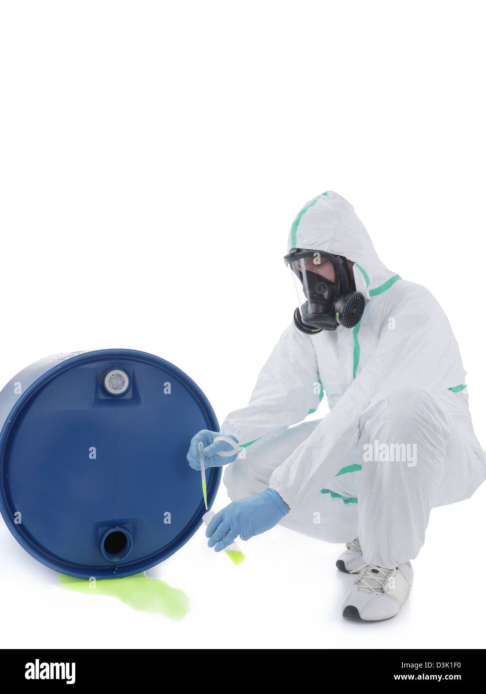 Man wearing protective suit and respirator sampling dangerous chemical liquid leaking from blue container Stock Photo