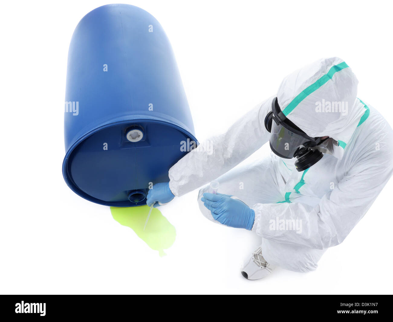 Man wearing protective suit and respirator sampling dangerous chemical liquid leaking from blue container Stock Photo