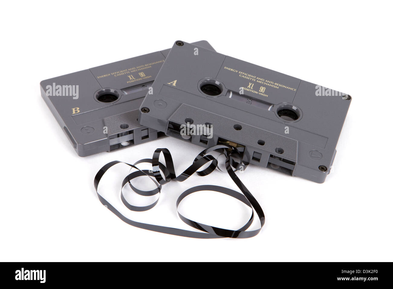 Obsolete magnetic audio cassette tapes partially unwound on a white background. Stock Photo