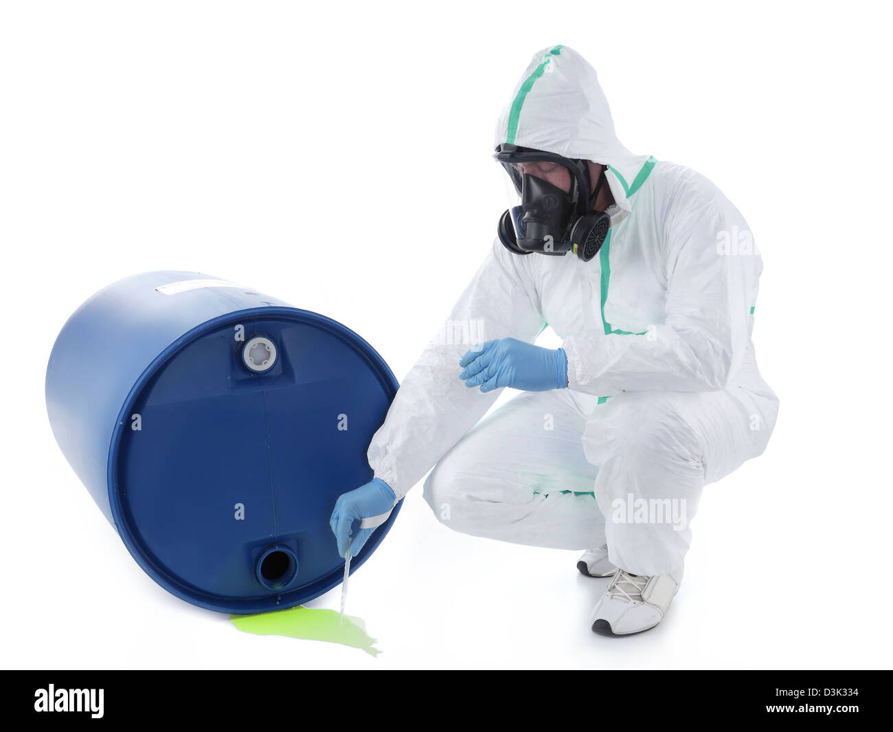Man wearing protective suit and respirator sampling dangerous chemical liquid leaking from blue container Stock Photo
