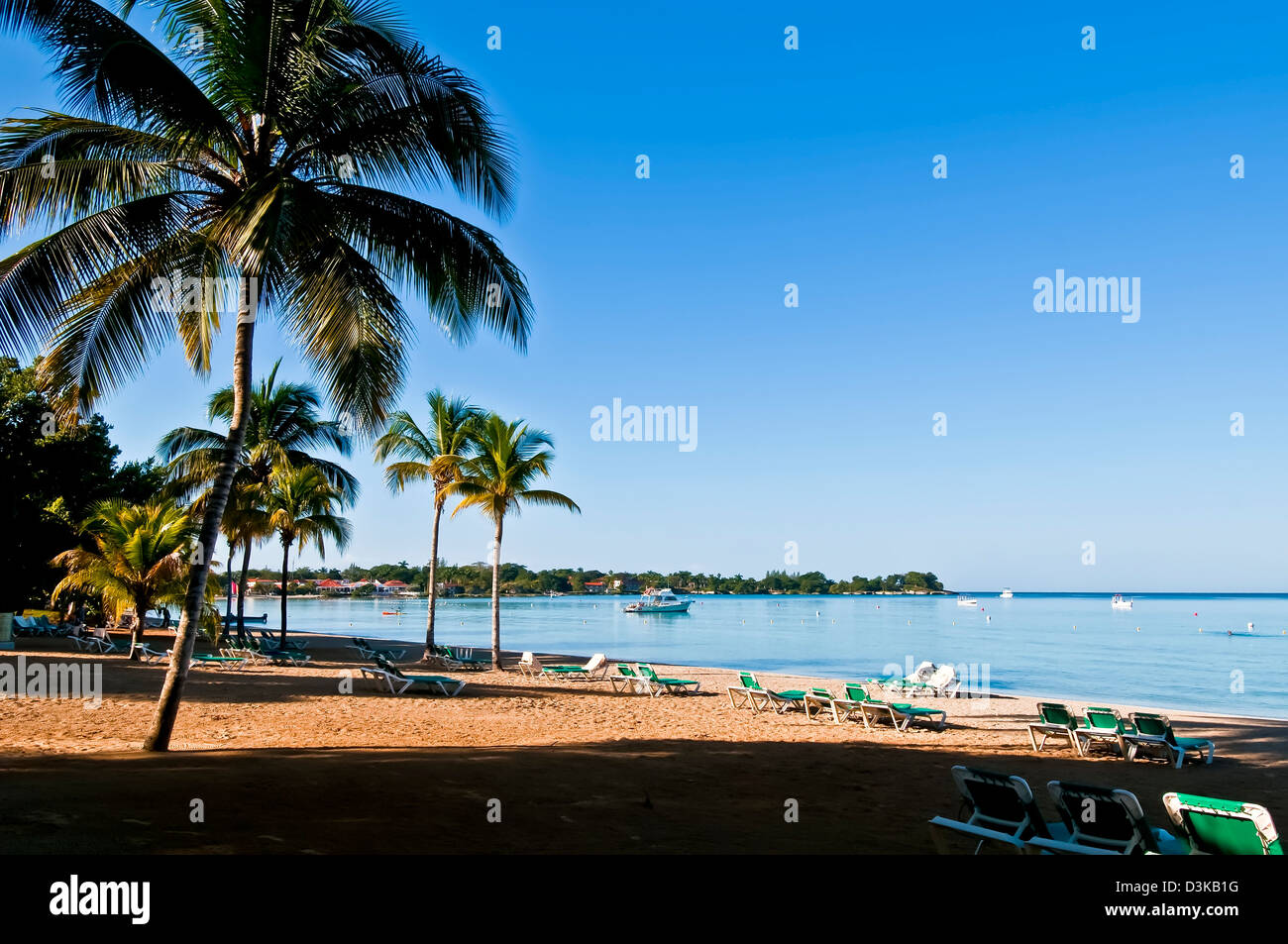 Deserted Negril beach flanked by coconut palm trees early in the morning Stock Photo