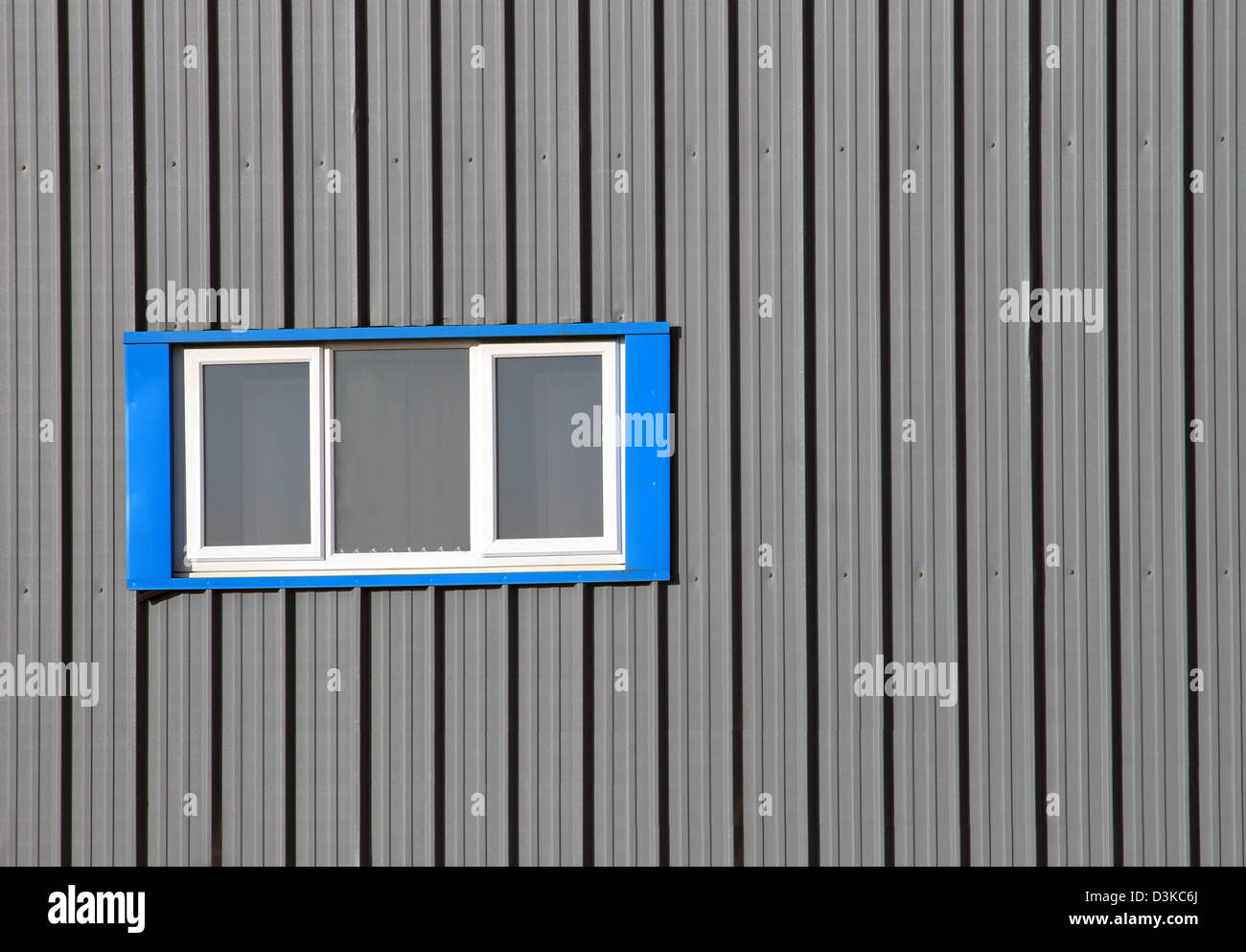 Blue window on modern industrial building with gray corrugated iron. Stock Photo