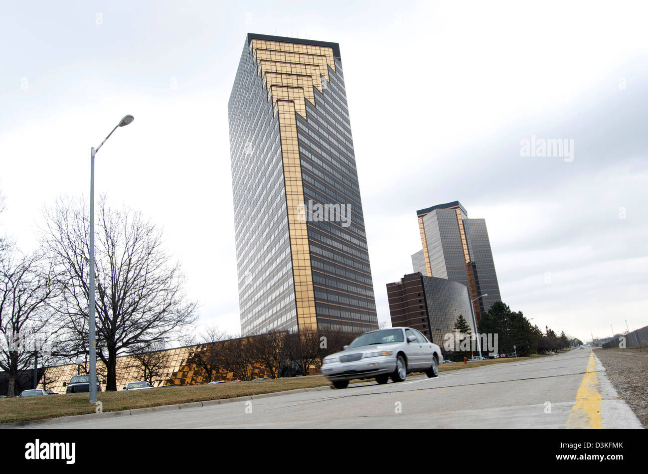 Low profile of a roadway with corporate buildings in the background and a car driving. Stock Photo