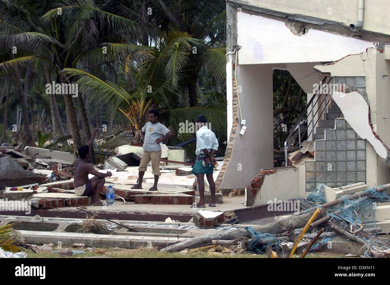 (dpa) - Three men stand on the remains of a house in the village of Dellewatha, near the city of Galle, Sri Lanka, 2 January 2005. Hundreds of thousands of people living in the coastal areas of Sri Lanka lost their homes and around 30,000 people were killed by a devastating tsunami caused by a seaquake on 26 December 2004. Stock Photo