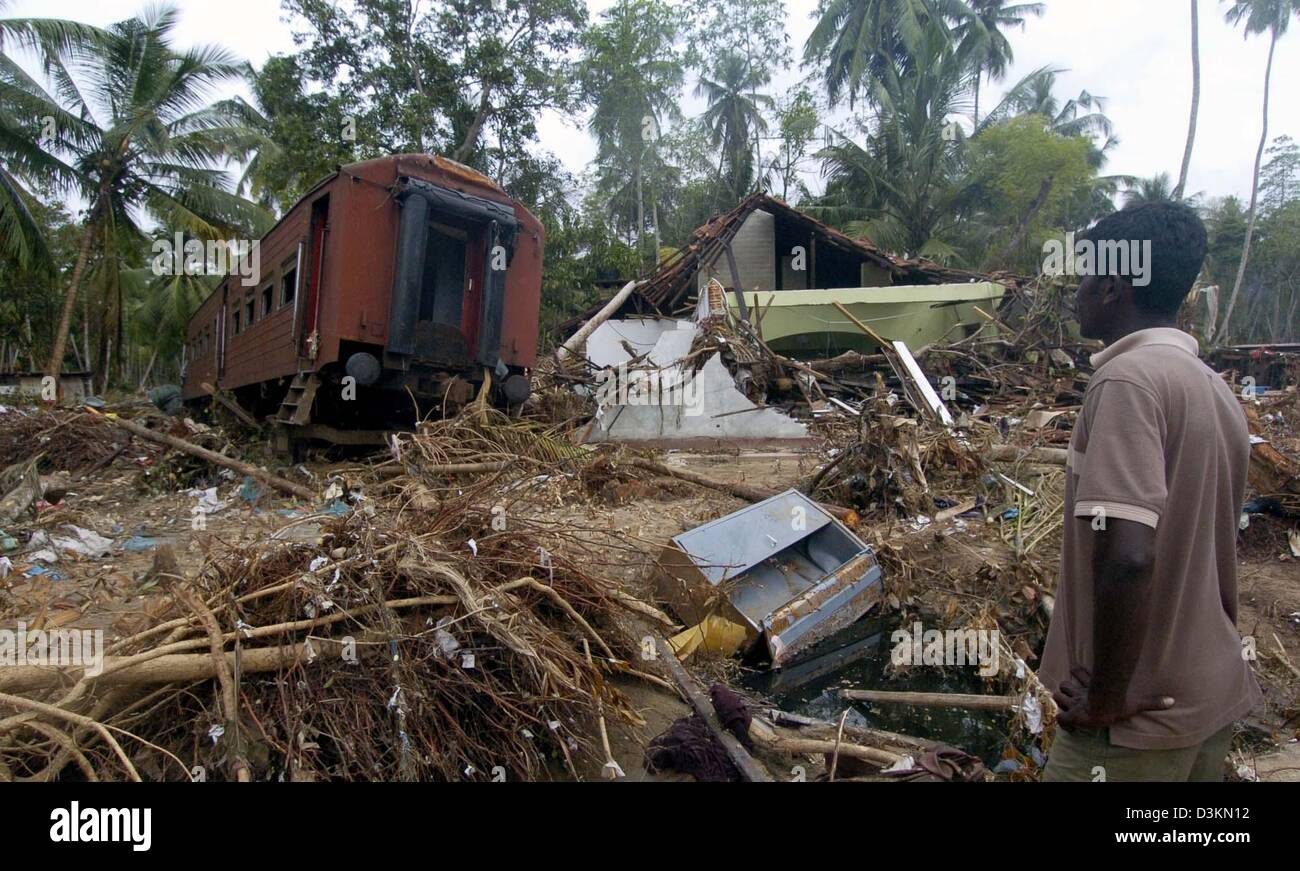 (dpa) - A man looks at a derailed train coach laying next to a destroyed house in the town of Dellewatha near the city of Galle, Sri Lanka, 2 January 2005. Hundreds of thousands of people living in the coastal areas of Sri Lanka lost their homes and around 30,000 people were killed by a devastating tsunami caused by a seaquake on 26 December 2004. Stock Photo