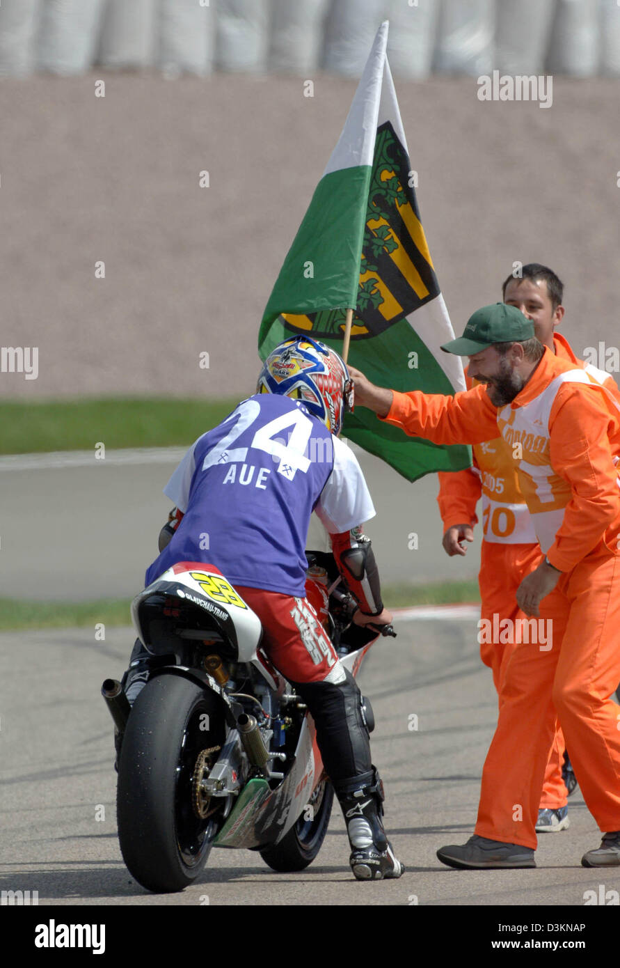 (dpa) - German motorbike pilot Dirk Heidolf gets a flag of Saxonia and a jersey of Wismut Aue from a track post after the 250cc category race at the Sachsenring race track near Hohenstein-Ernstthal, Germany, Sunday 31 July 2005. The honda pilot who finished the race in 13th place comes from Hohenstein-Ernstthal, Germany. Photo: Matthias Hiekel Stock Photo