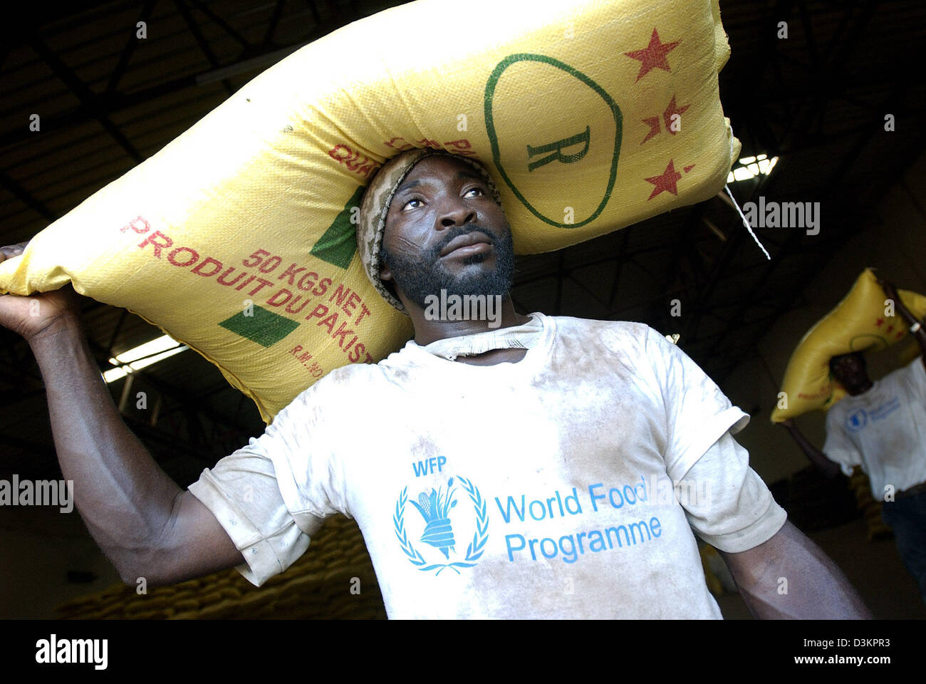 (dpa) - A World Food Programme (WFP) volunteer caries a sack of grain out of the warehouse in the town of Maradi, Niger, Saturday 13 August 2005. Hunger, a perennial problem in Niger, Mali, Mauritania and Burkina Faso, was compounded by a locust invasion last year followed by drought. The UN says millions now face severe food shortages. Photo: Marcel Mettelsiefen Stock Photo