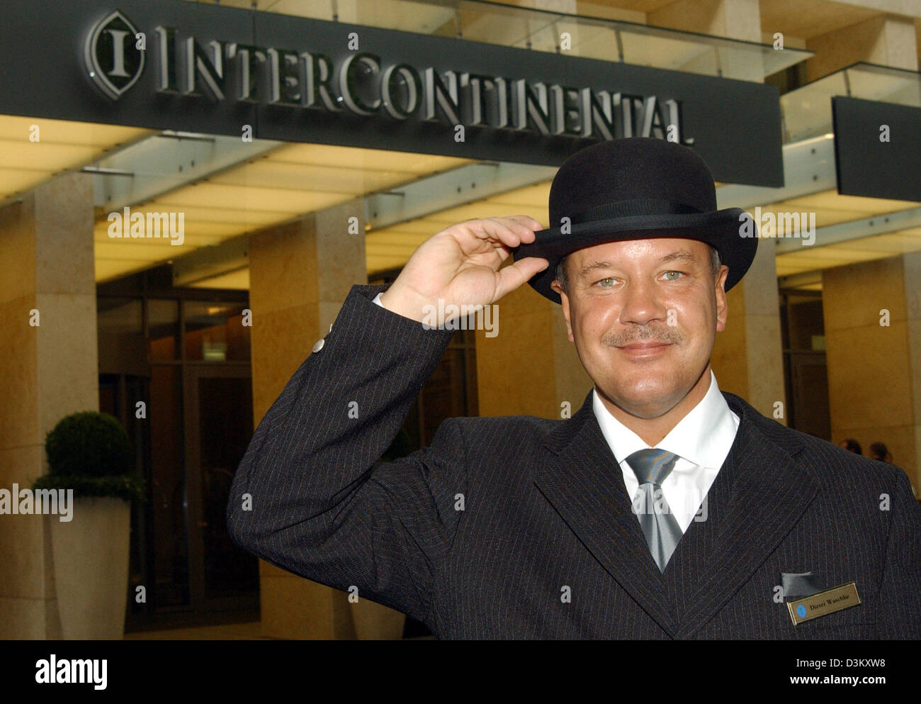 (dpa) - Doorman Dieter Waschke (44) smiles as he tipps his hat as a welcome gesture at the five star InterContinental-Hotel in Duesseldorf, Germany, 25 September 2005. The luxurious hotel was finally opened at the beginning of September 2005 following three years of construction and an investment of 176 million euros. 160 staff, from the porter to the concierge, are taking care of  Stock Photo