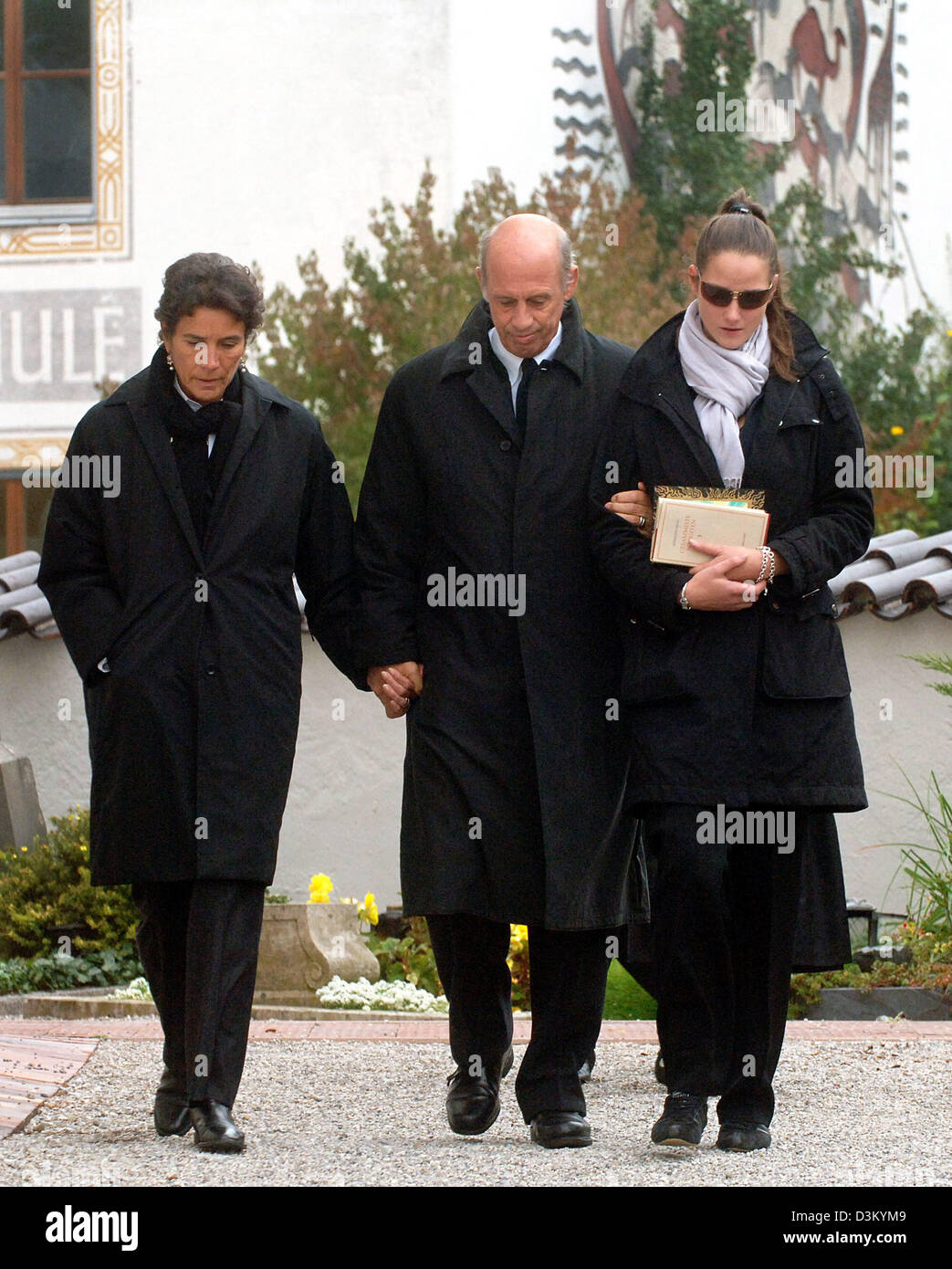 dpa) - German fashion designers Willy Bogner (C) and Sonia Bogner (L) and  their daughter Florinda (R) walk over to the funeral service for their son  Bernhard at the cemetery in Gmund