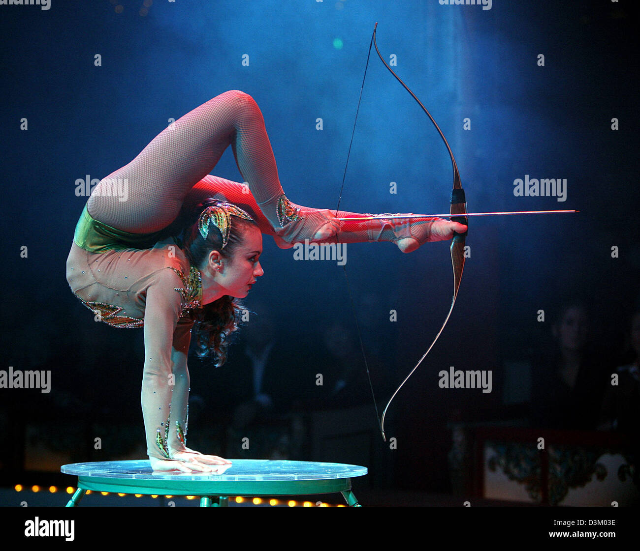 (dpa) - A contorsionist lets off an arrow with her feet during her performance in the Circus Roncalli in Frankfurt, Germany, 8 October 2005. The circus guests for the first time after many years in the Main river metropole. Photo: Frank Rupenhorst Stock Photo