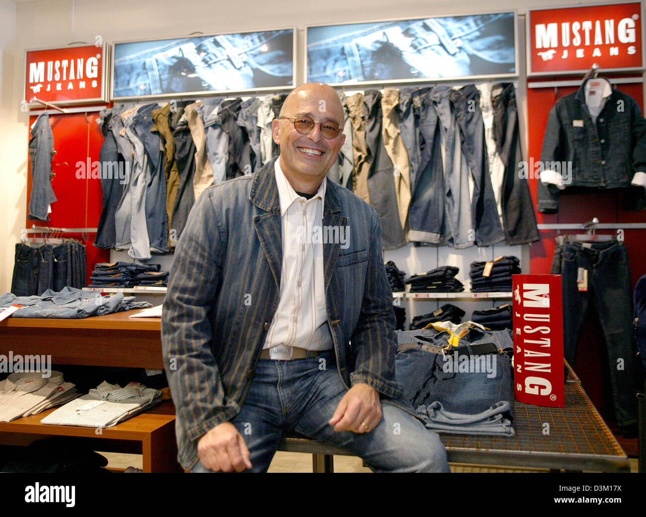 dpa file) - Mustang Jeans managing director Heiner Sefranek smiles in front  of Mustag Jeans products in