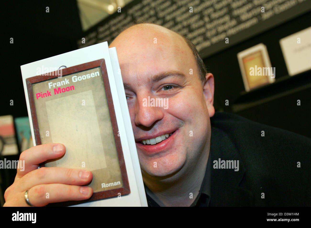 (dpa) - German author Frank Goosen holds his latest novel 'Pink Moon' in front of his face and smiles at the international book fair in Frankfurt, Germany, 20 October 2005. Photo: Uwe Zucchi Stock Photo