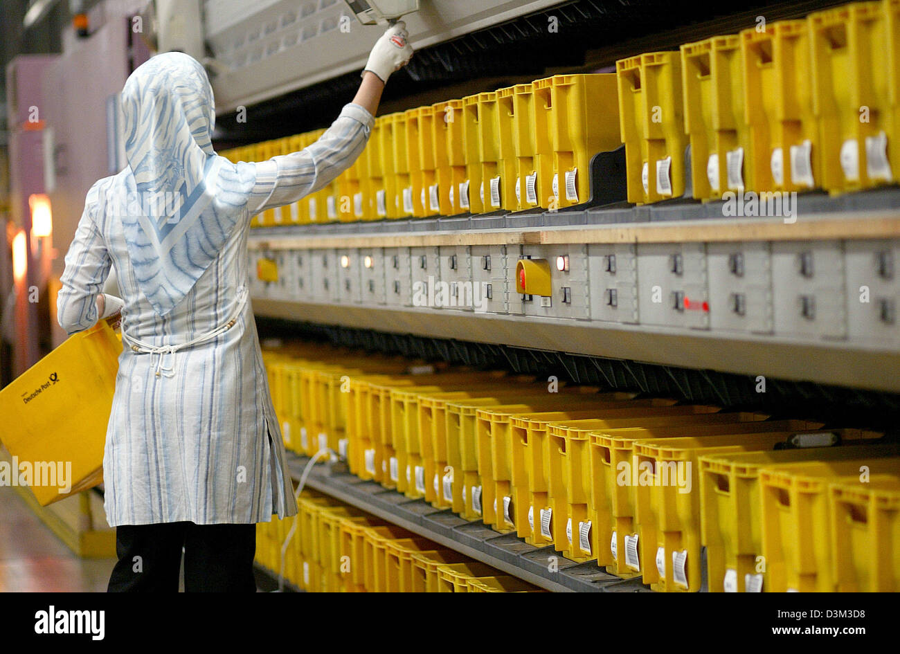 (dpa) - An employee of the Deutsche Post World Net operates an oversized letters sorting machine in the Mail Logistic Centre in Spich near Bonn, Germany, 21 July 2005. The Deutsche Post World Net employs circa 127,000 employees in the branch 'Letter National' handling and delivering an average of 70 million sendings per day. Photo: Felix Heyder Stock Photo