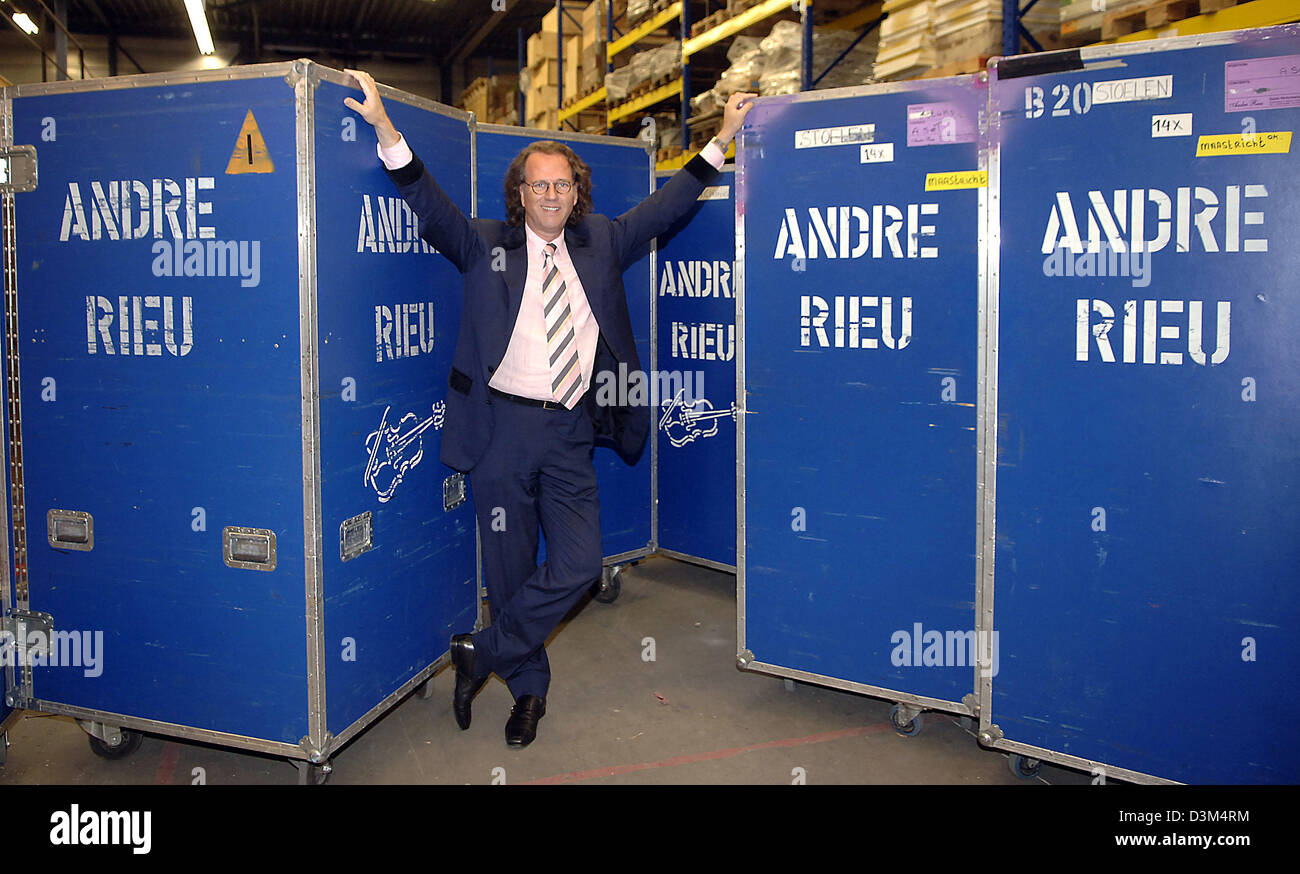 (dpa) - Dutch star violinist Andre Rieu smiles while standing between two large containers featuring his name at his warehouse in Maastricht, the Netherlands, 02 November 2005. The 56-year-old musician is about to start the first part of his tour through Canada and the USA, where he will perform at 13 mayor cities. The complete equipment of his crew, which numbers 40 people, was al Stock Photo