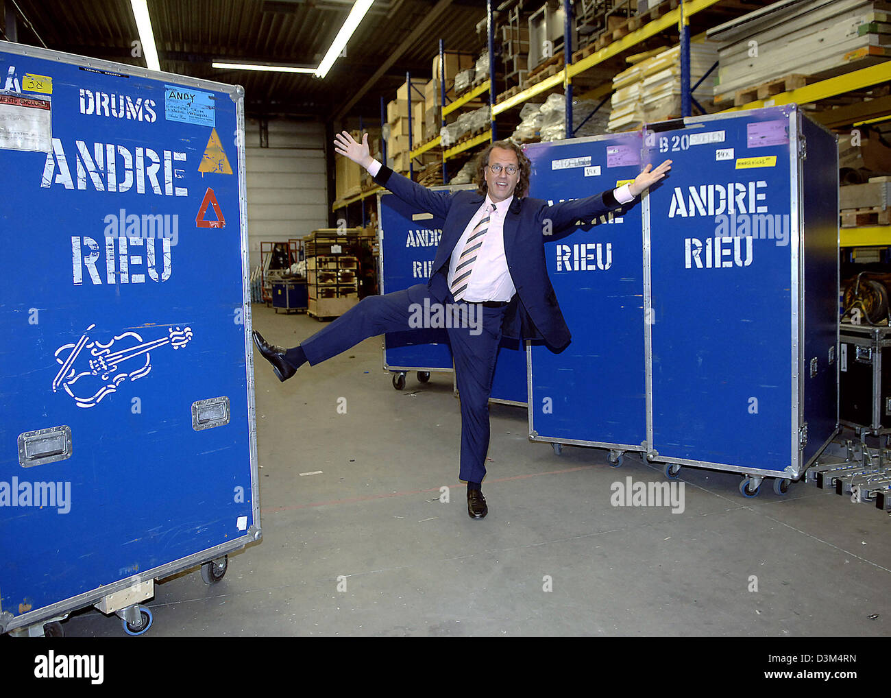 (dpa) - Dutch star violinist Andre Rieu poses jokingly between large containers featuring his name at his warehouse in Maastricht, the Netherlands, 02 November 2005. The 56-year-old musician is about to start the first part of his tour through Canada and the USA, where he will perform at 13 mayor cities. The complete equipment of his crew, which numbers 40 people, was already loade Stock Photo